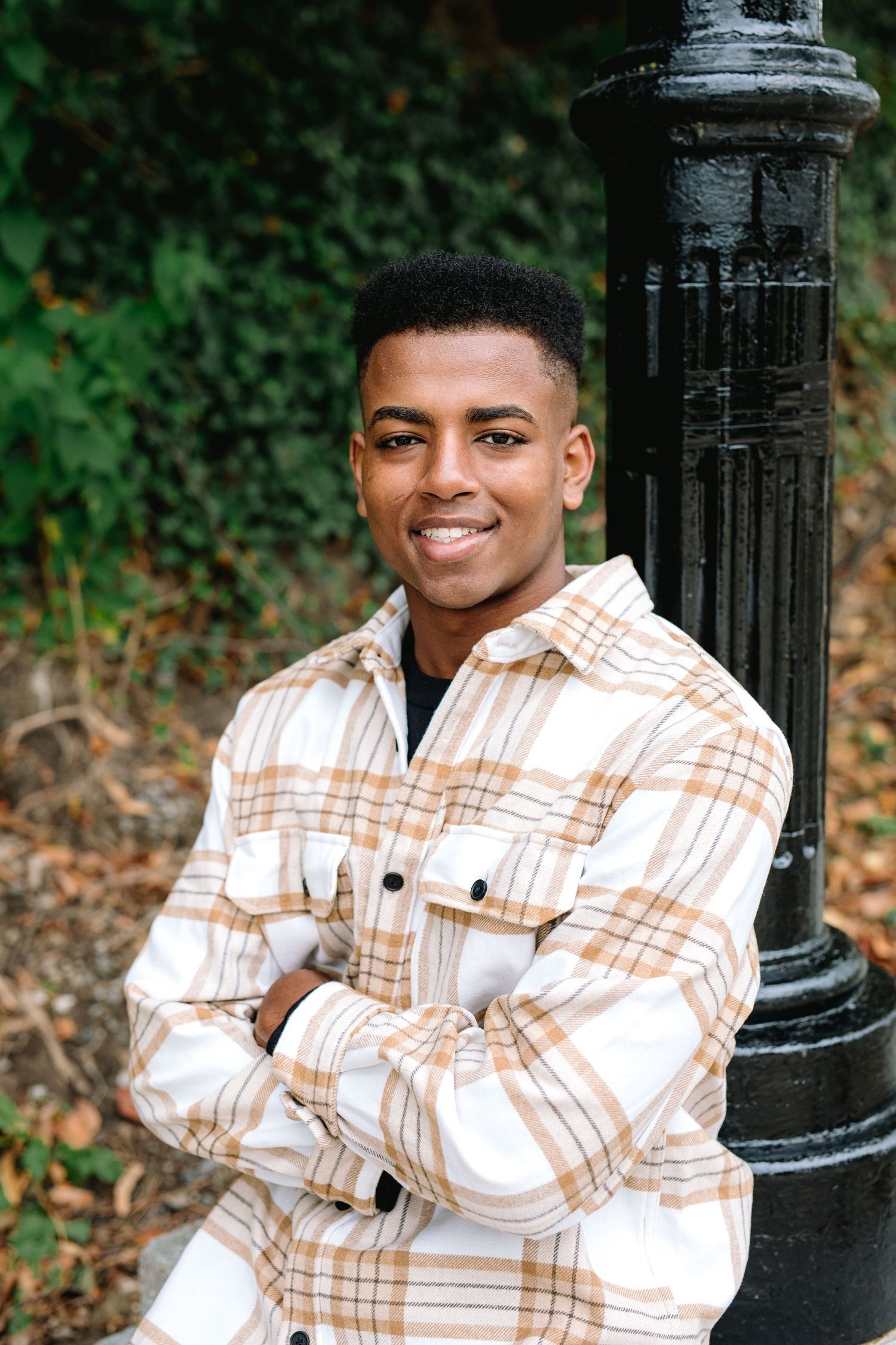 High School Senior Tommy poses leans against a lamp post during his senior session at hoyt lake in Delaware Park in Buffalo, New York.