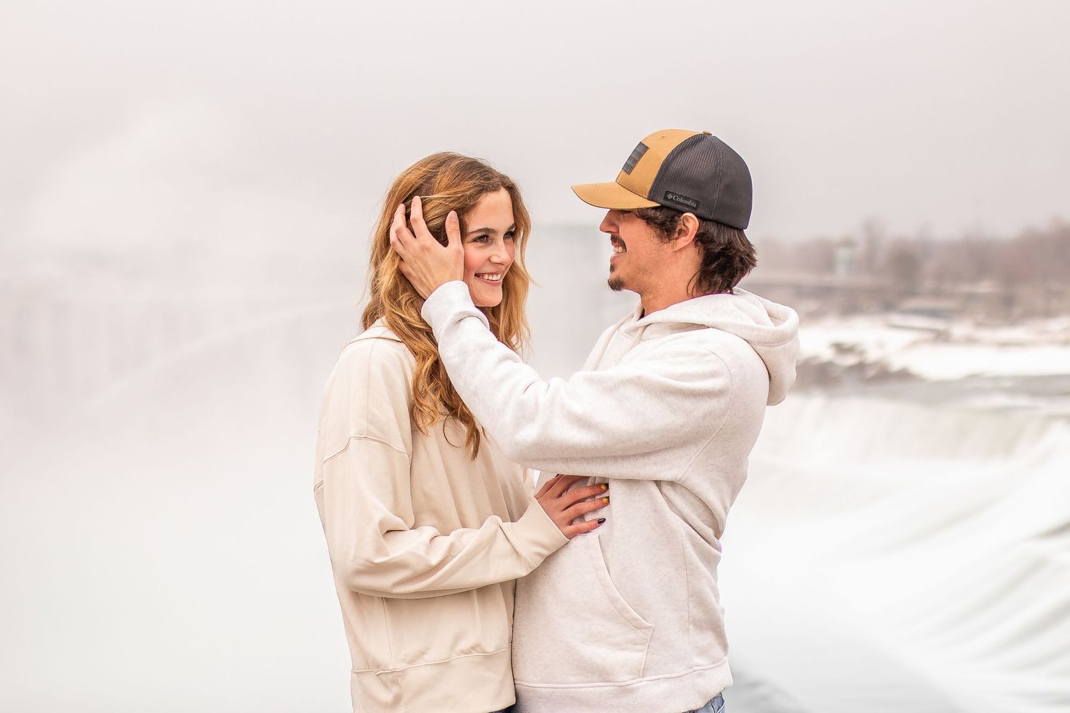 Newly engaged couple look at each other lovingly in front of Niagara Falls, New York after the surprise proposal during their engagement