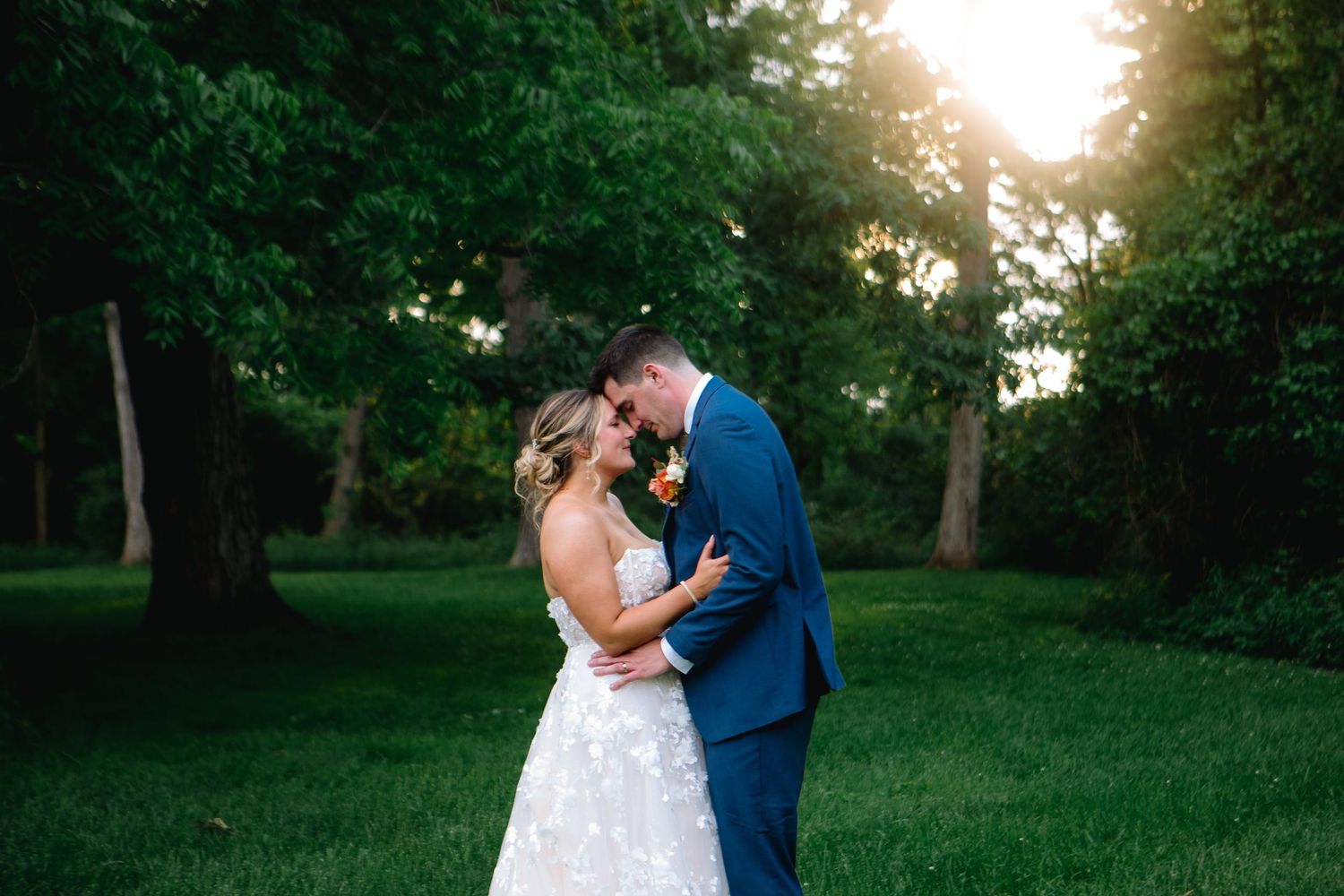 Newly married bride and groom embrace in a field after their wedding ceremony at The Cobblestone Wedding Barn in Scottsville, New York.