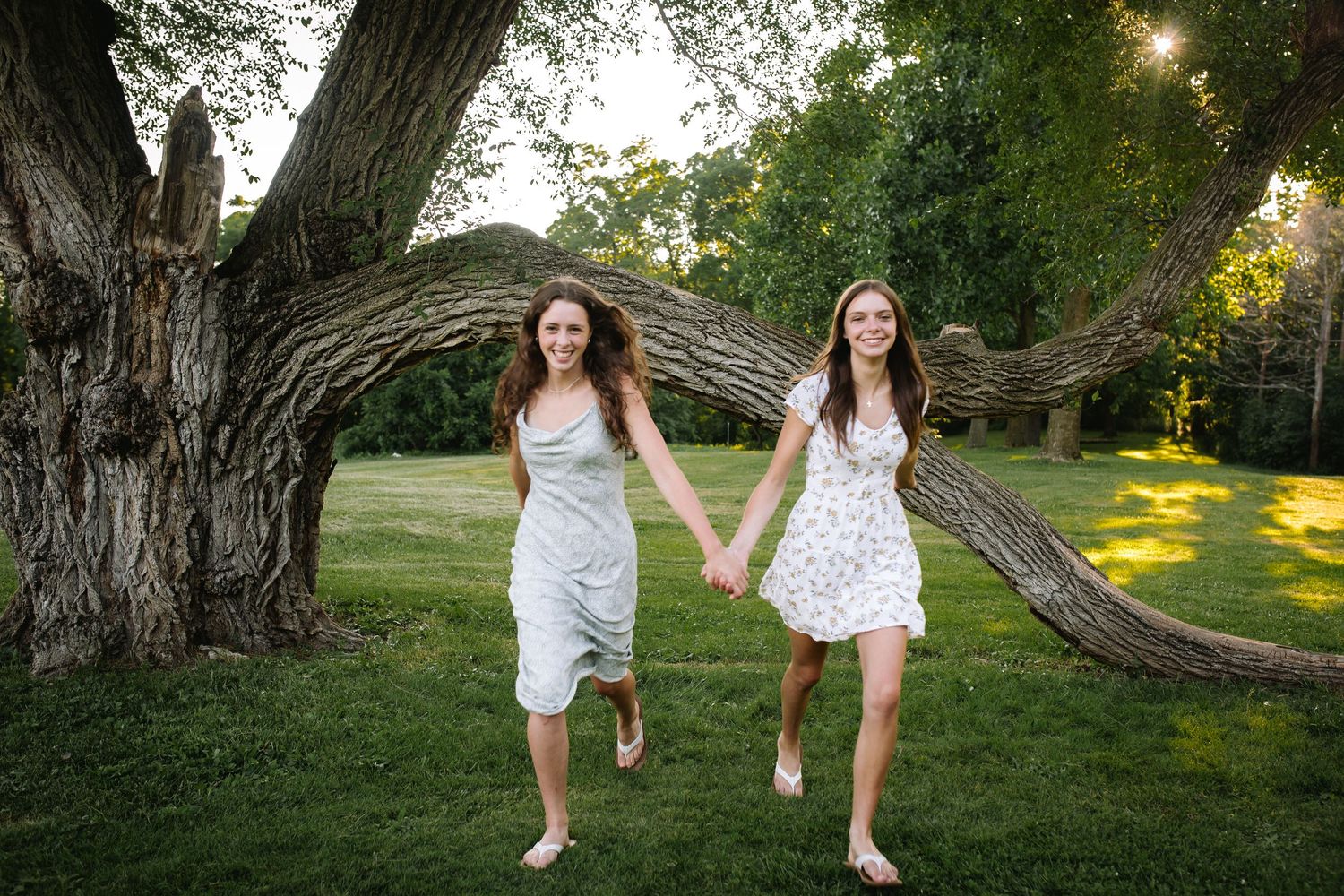 Sisters hold hands in Bond Lake park in niagara county at their family session.