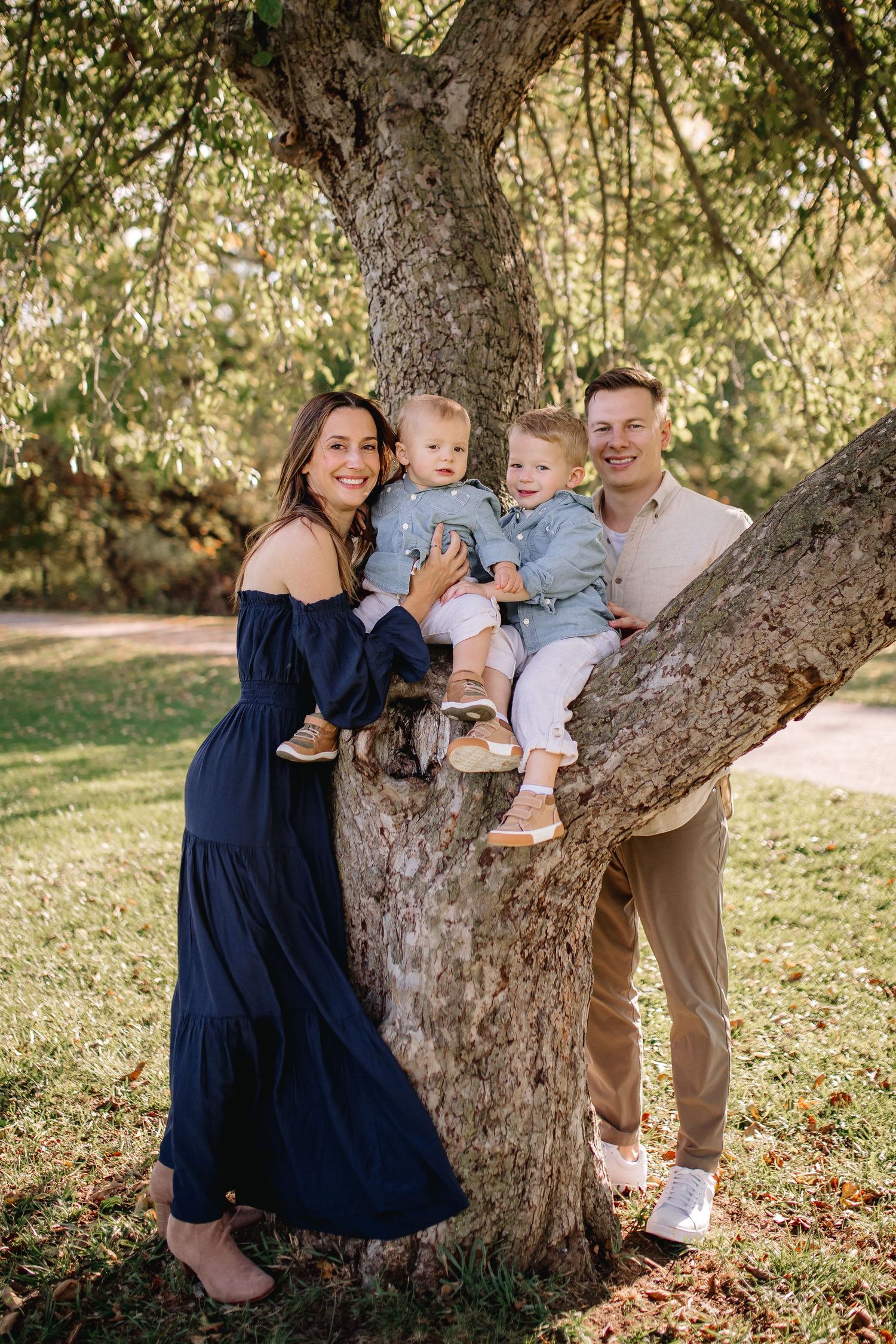 family of four pose in the tree at Amherst state park at their family session in Amherst, New York.
