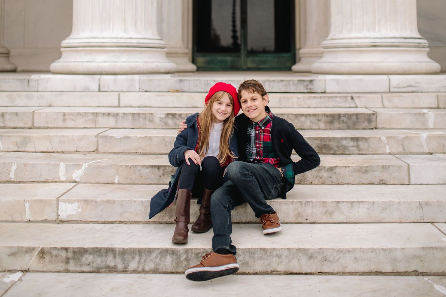 Brother and sister pose head to head on steps at Delaware Park in Buffalo during their family portrait session.
