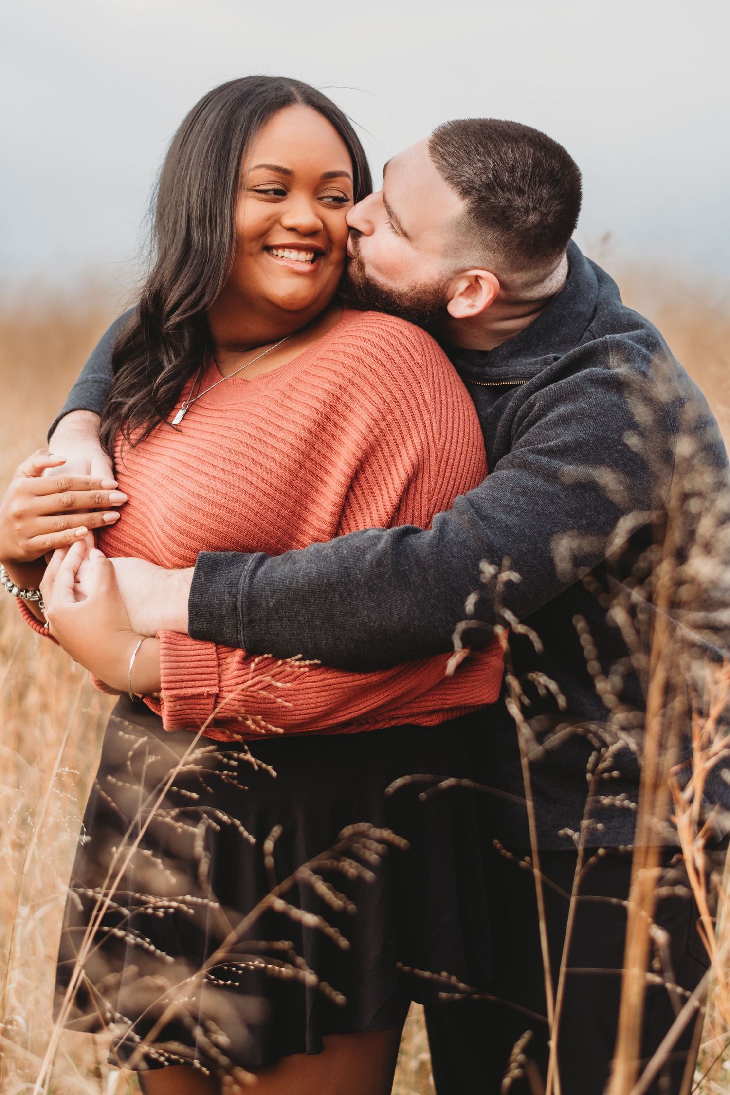 Romantic couple embracing in a field of tall autumn grass.
