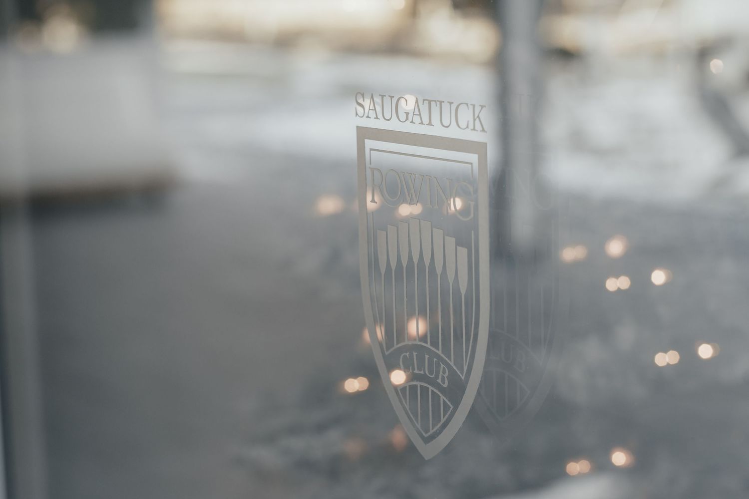 Vintage Saugatuck sign illuminated with soft bokeh lights in the background.