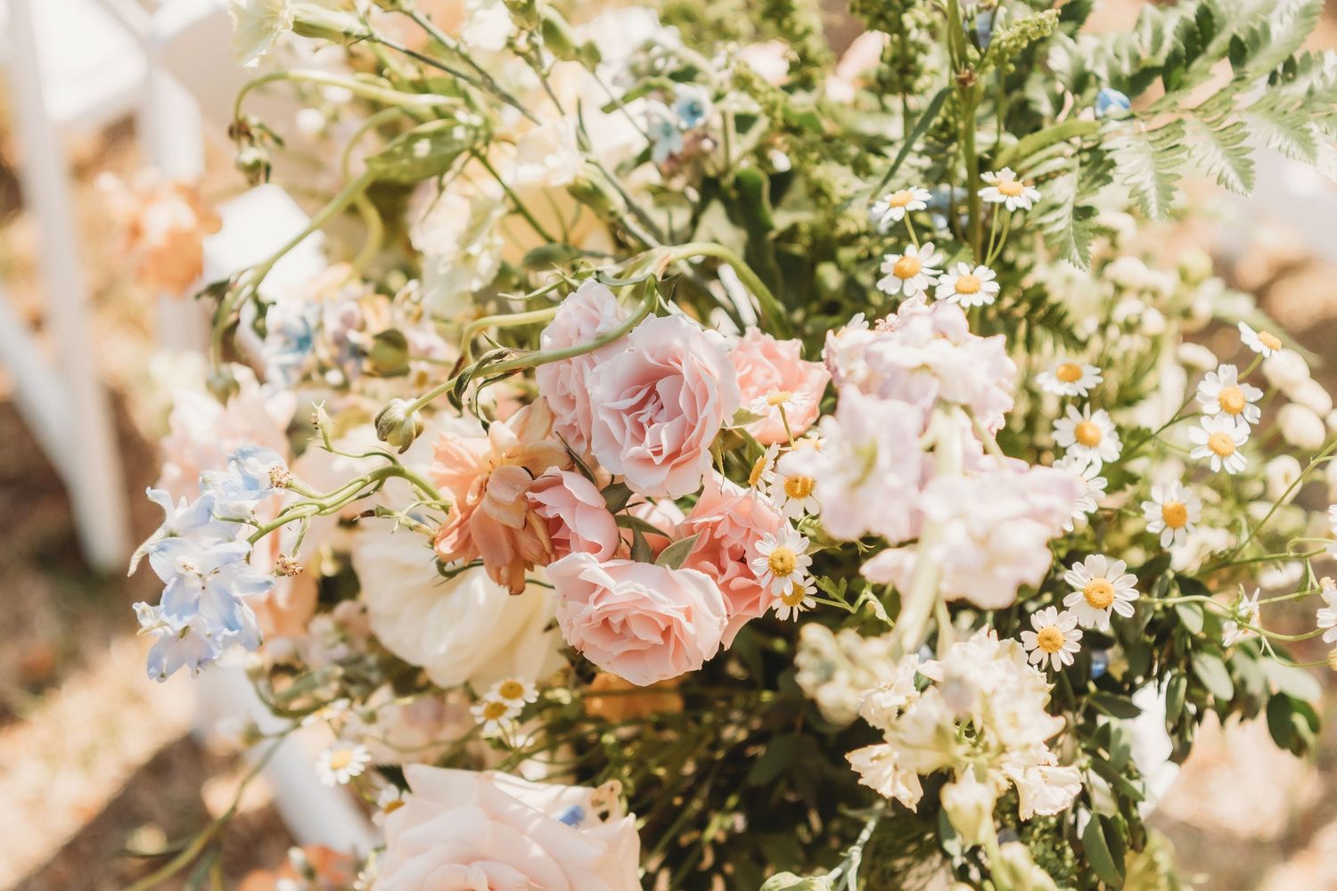 Elegant floral wedding centerpiece arrangement featuring pink roses and white flowers with lush greenery on a decorated table.