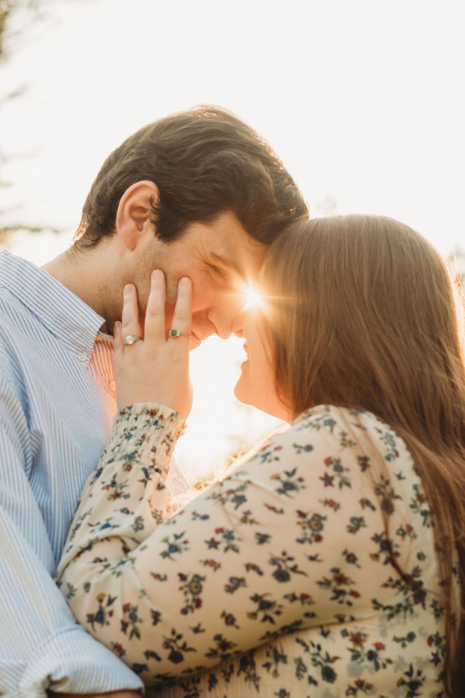Romantic couple embraces in warm sunlight during outdoor photo session.