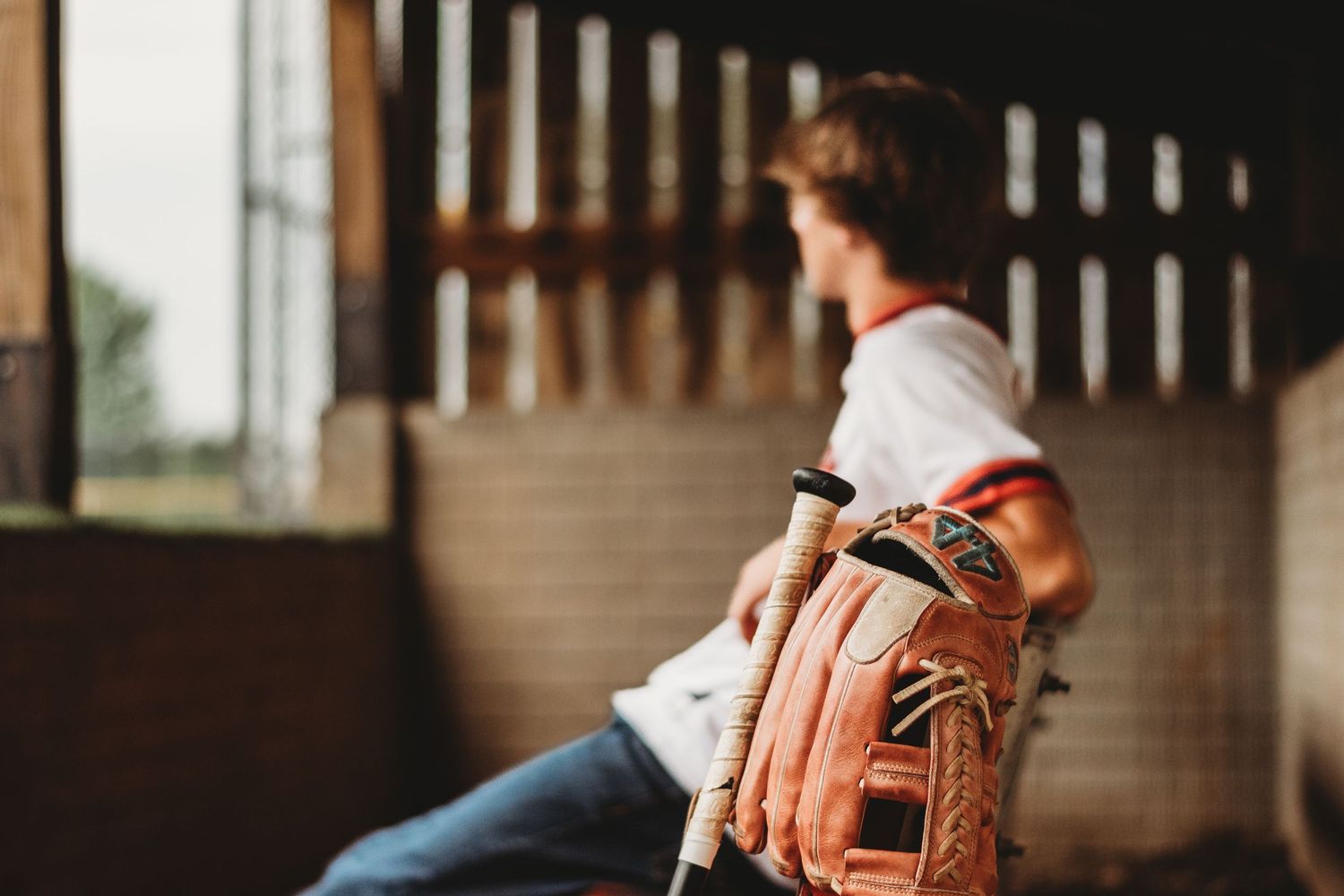 Baseball glove and equipment shown in dark indoor setting with dramatic lighting.