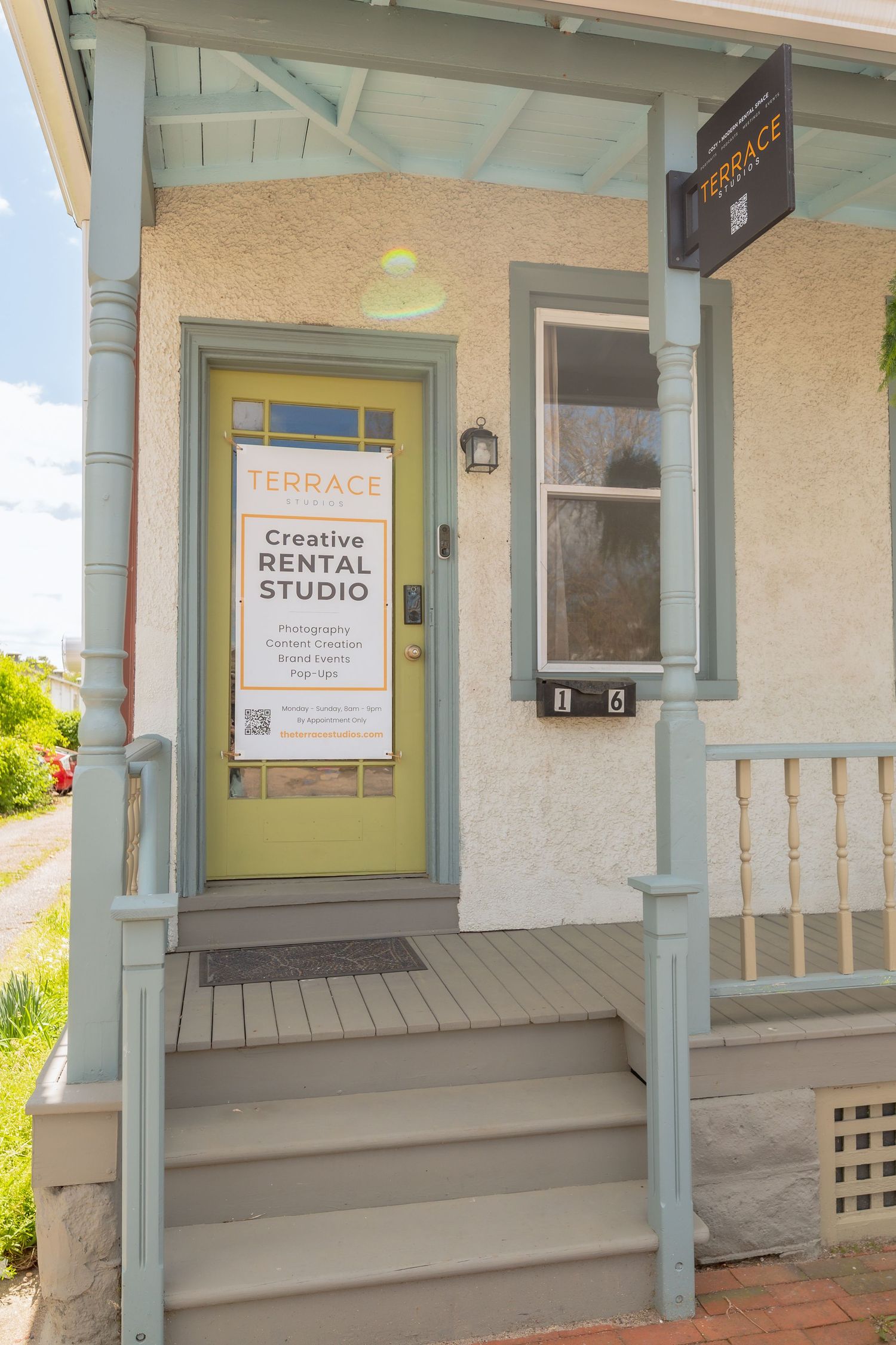 Exterior view of a creative rental studio with mint green trim and front porch.