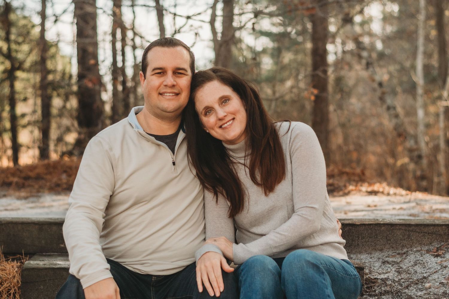 Happy couple in casual wear posing for outdoor portraits near water.