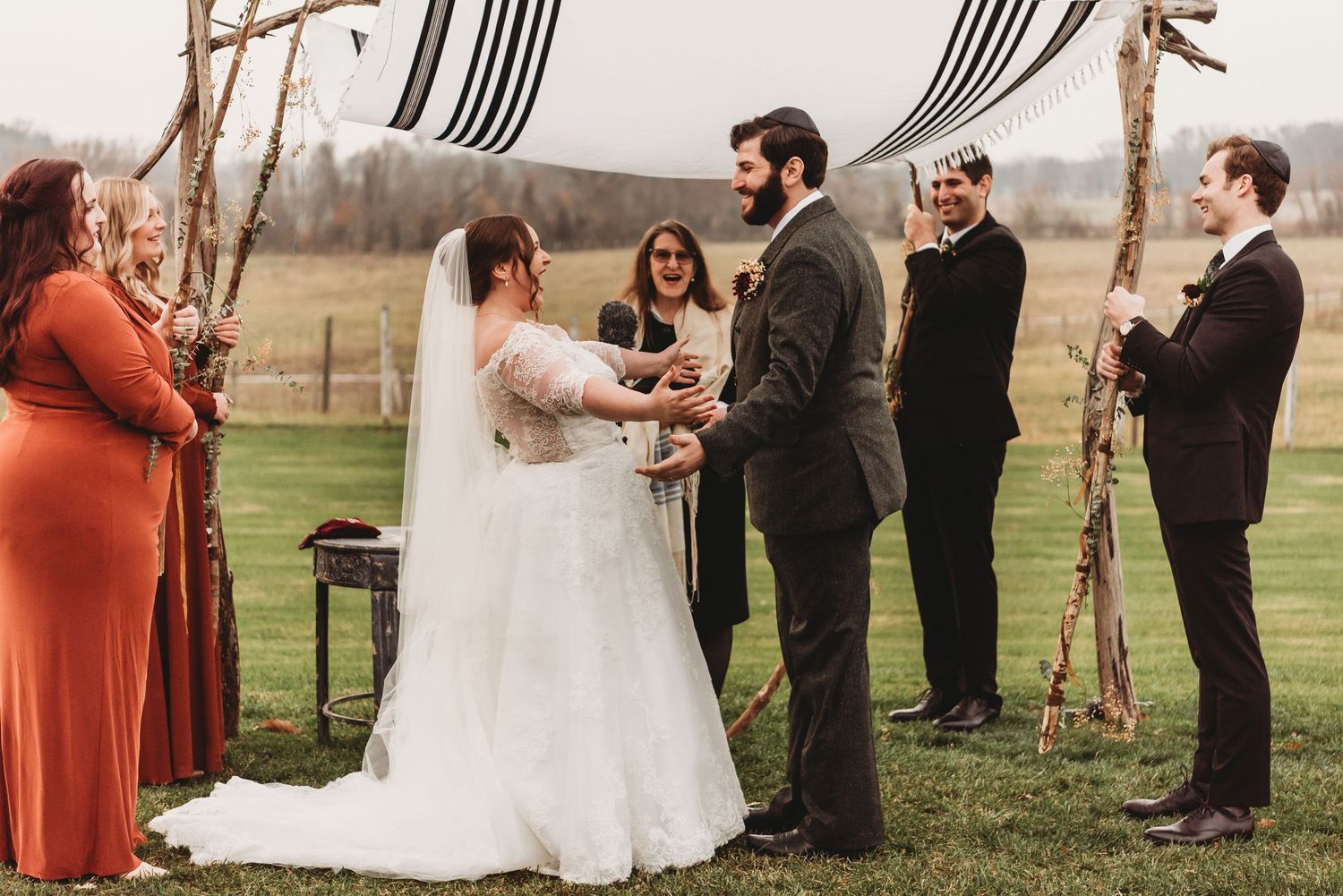 Outdoor wedding ceremony with guests gathered under autumn trees.
