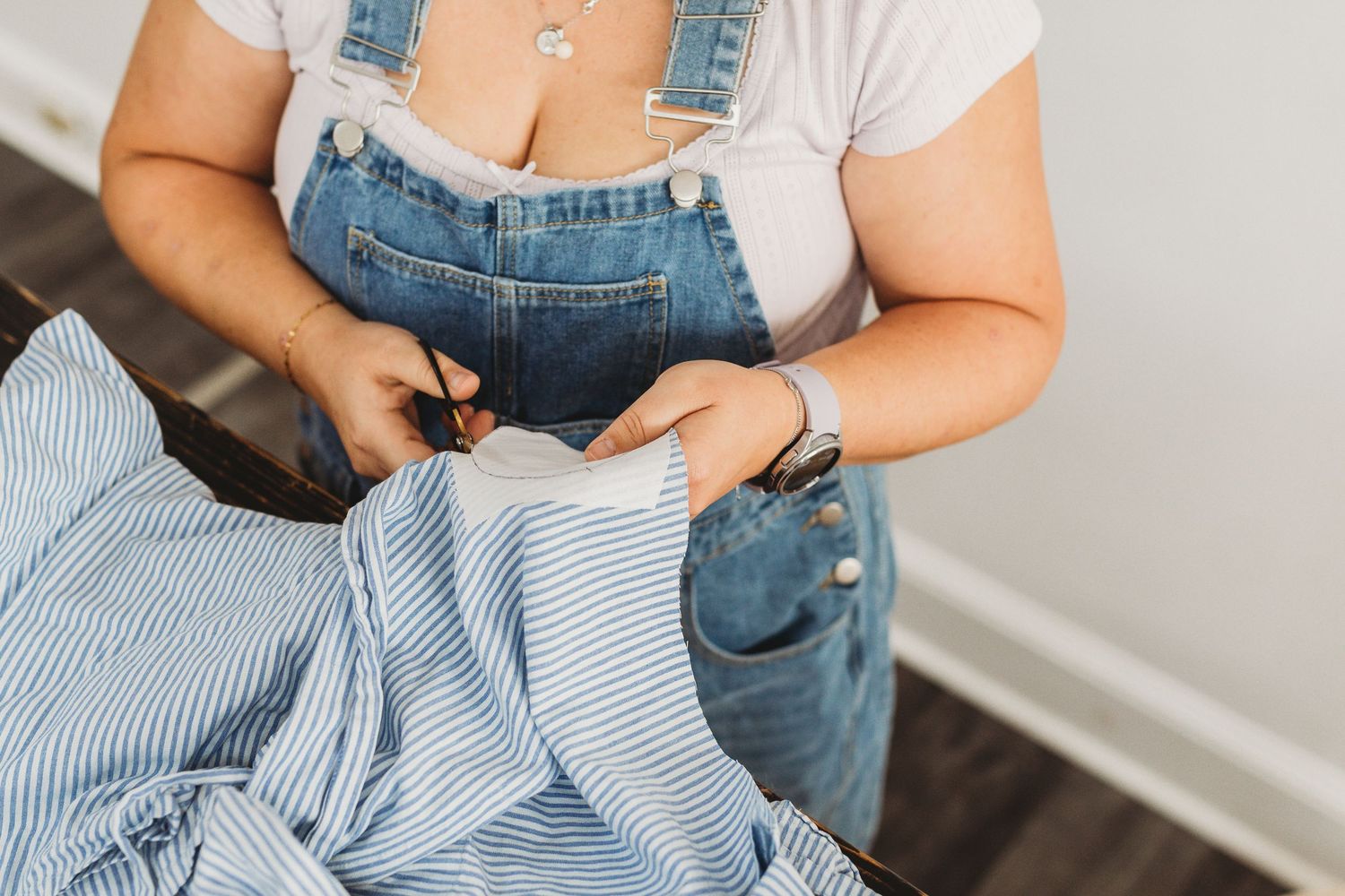 Person in denim and white clothing working with fabric at a sewing station.
