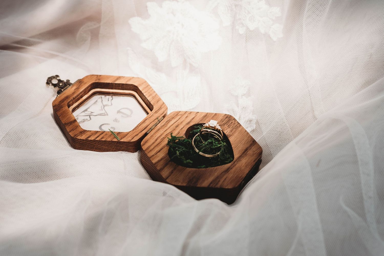 Wooden ring boxes displayed on flowing white tulle fabric.
