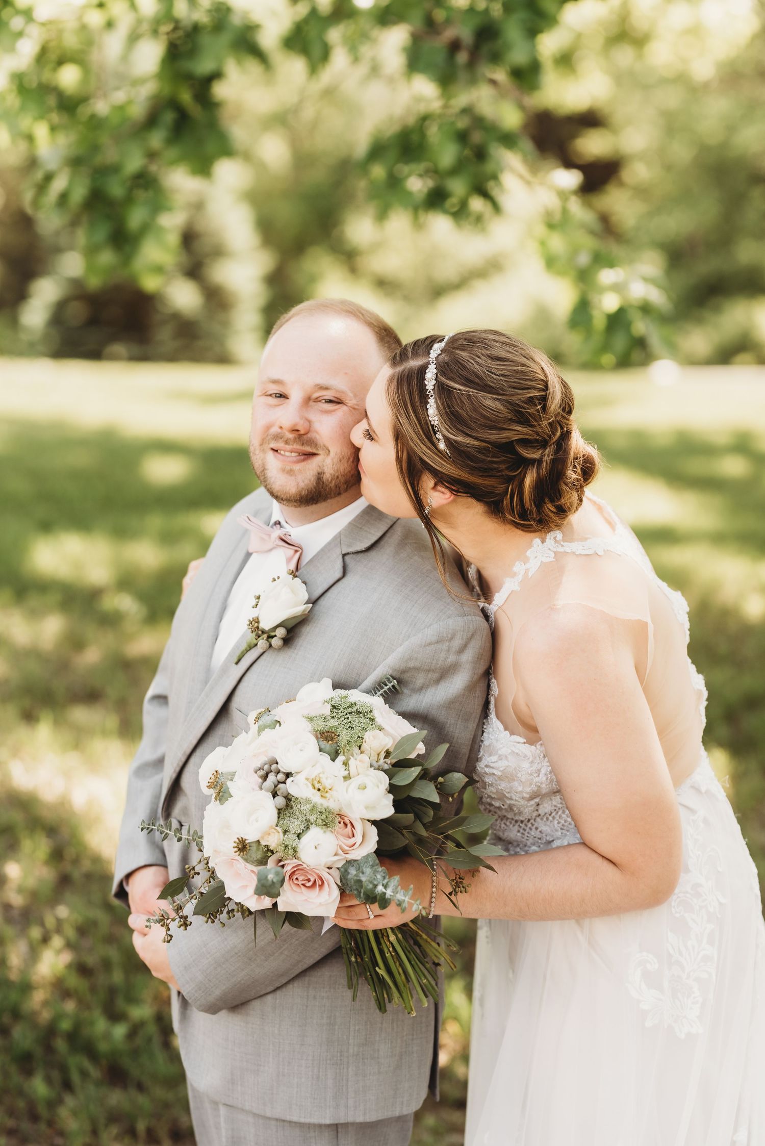 Joyful wedding couple sharing laughter in a sunny garden setting.