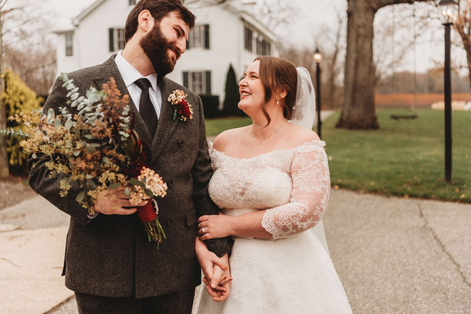 A romantic autumn wedding couple embraces outdoors surrounded by fall foliage.