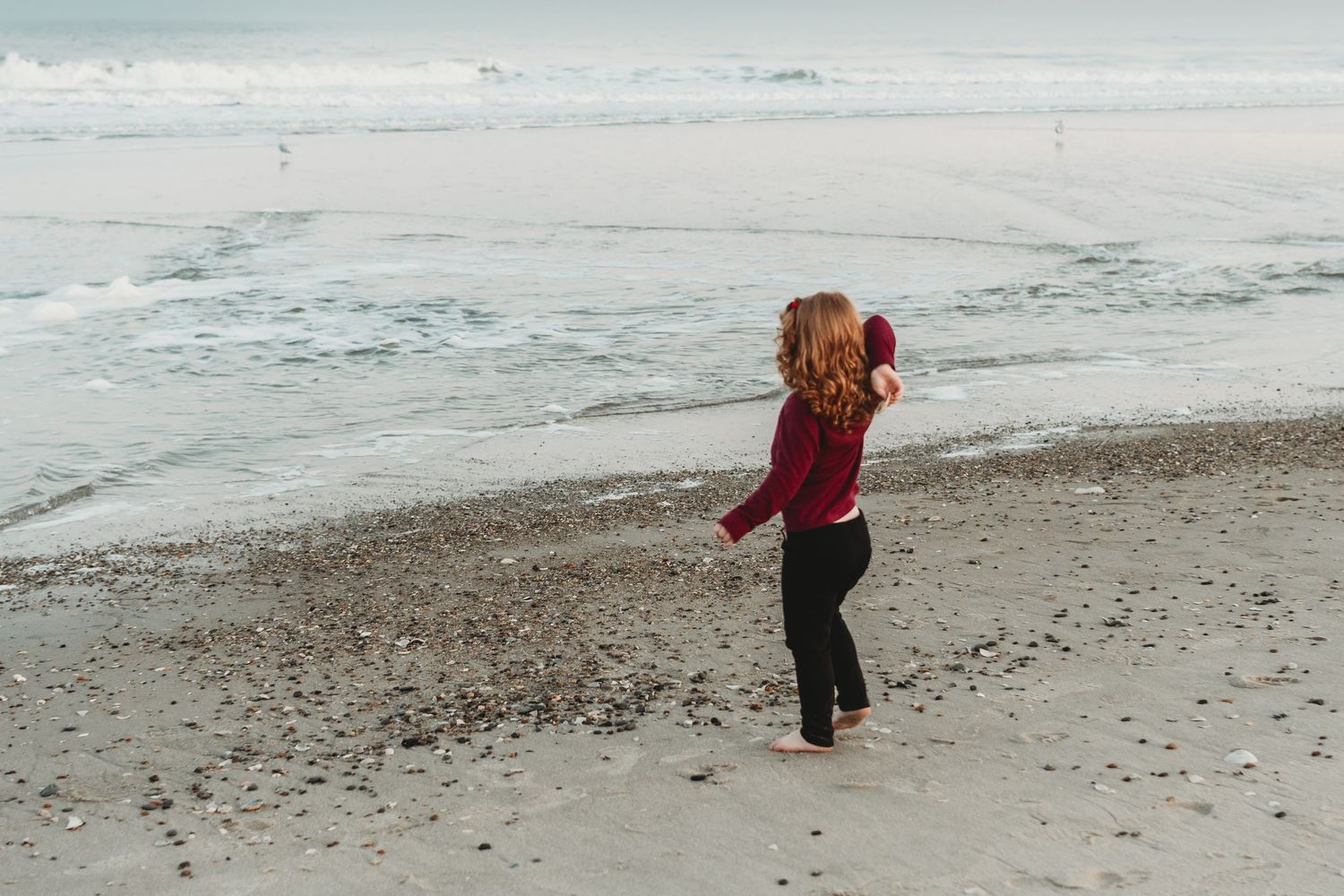 People enjoying a walk along the shoreline of a beach.