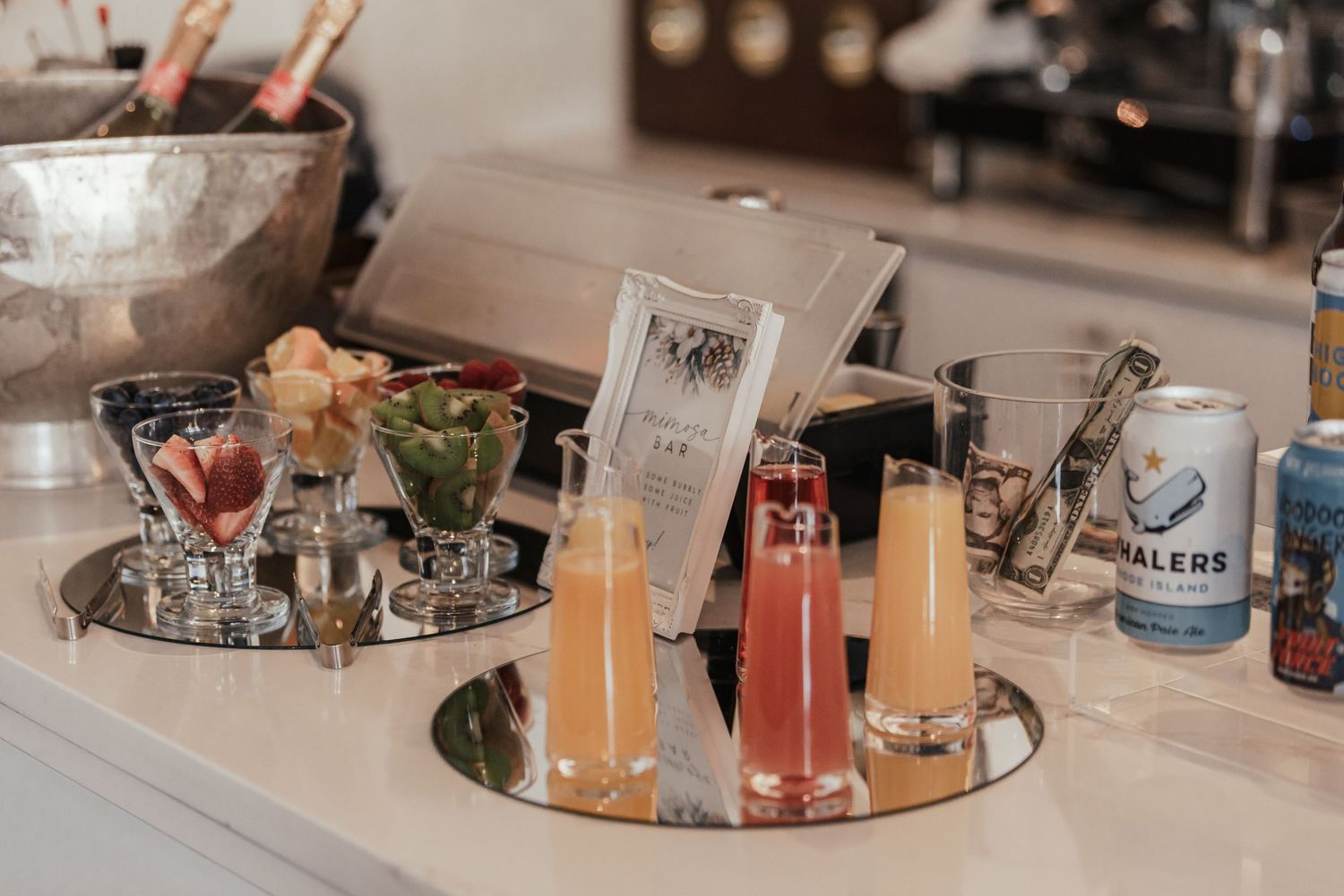 Wedding bar setup featuring colorful signature cocktails and drink displays on mirrored tray.