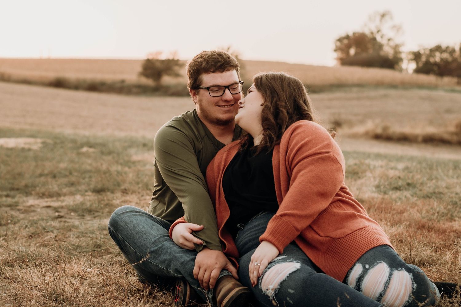 Couple in casual attire sharing intimate moments in autumn field setting.