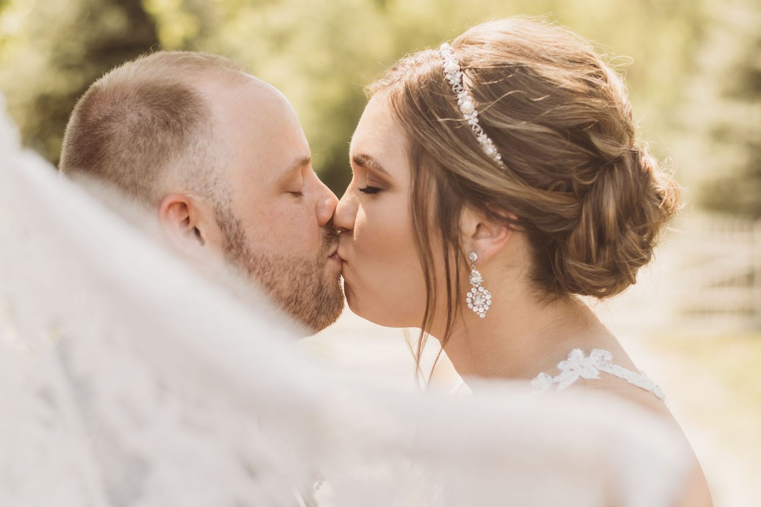 Wedding couple sharing kiss while bride holds bouquet.