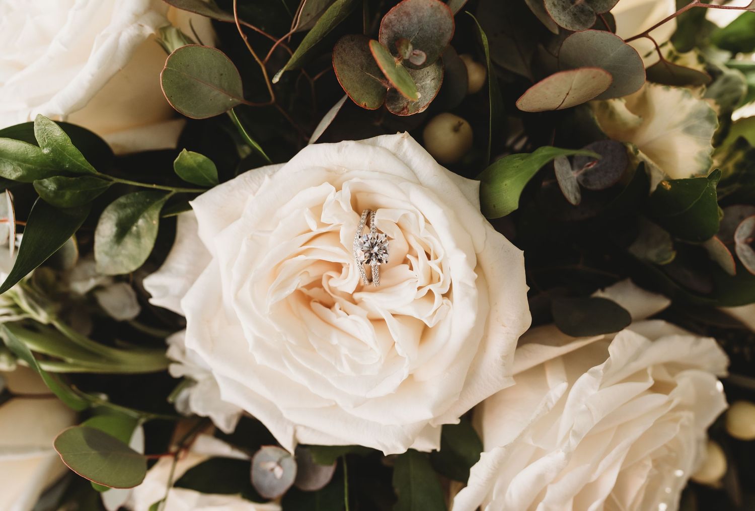 Delicate white roses and greenery arranged in an elegant wedding floral display.
