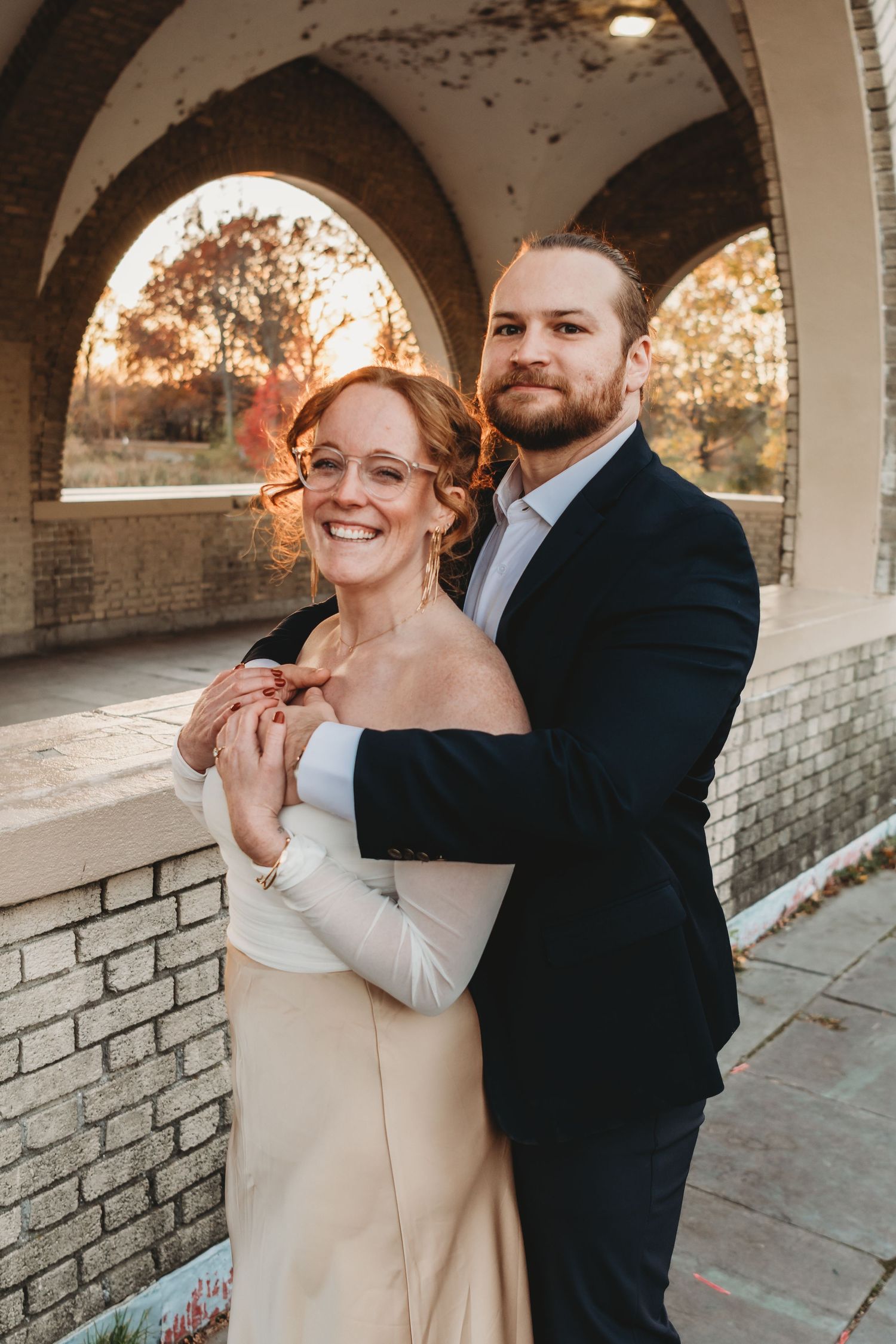 Sweet moment captured under white stone arches during a wedding photoshoot.