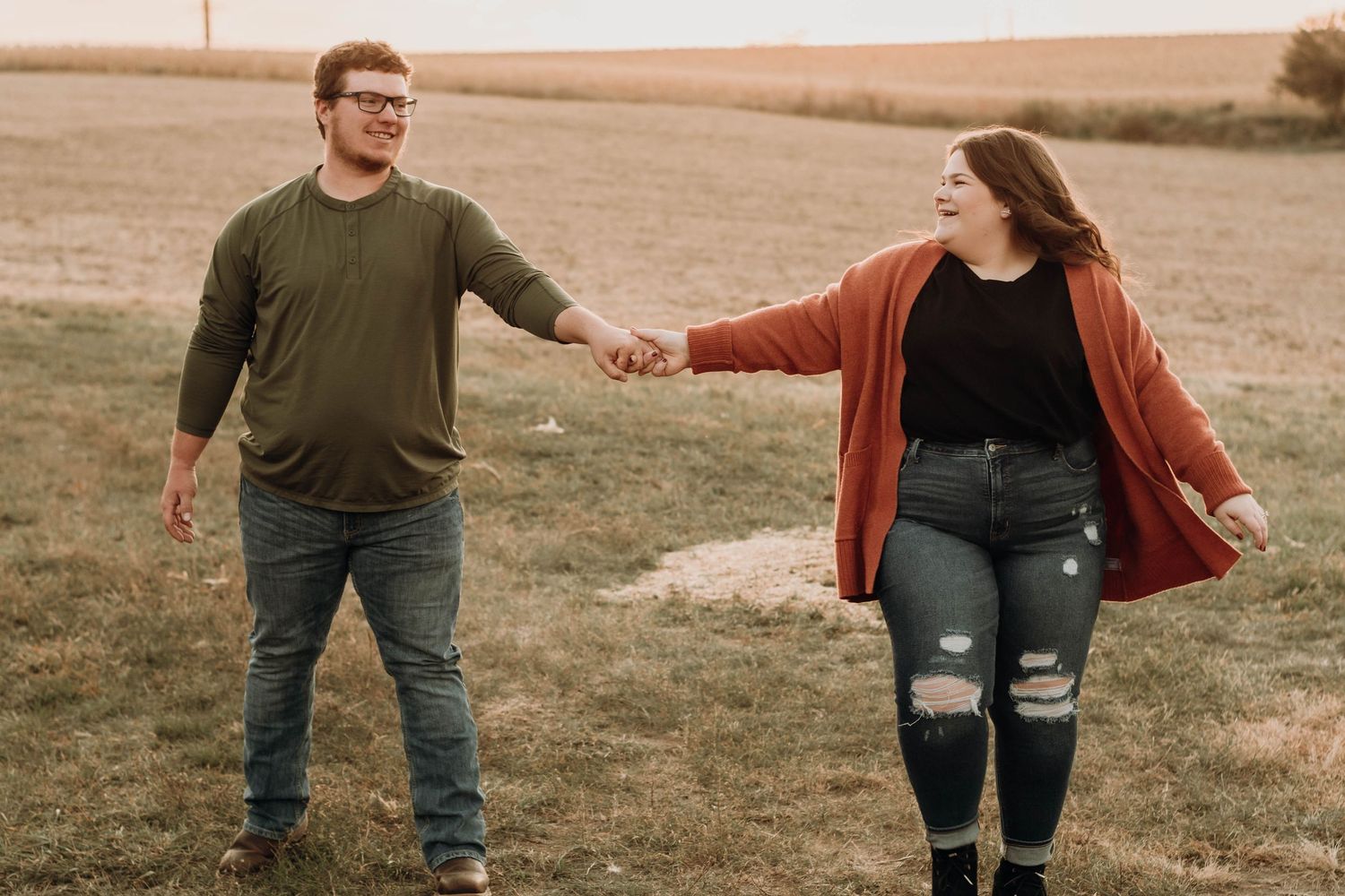 Casual couple in autumn clothing sharing playful moments in open field.