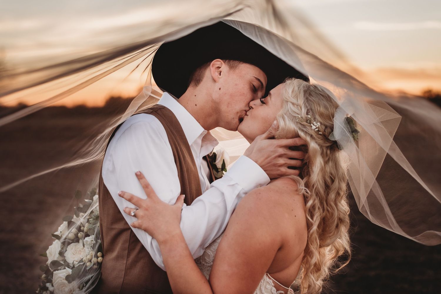 Romantic sunset wedding portraits with flowing veil and warm golden light.