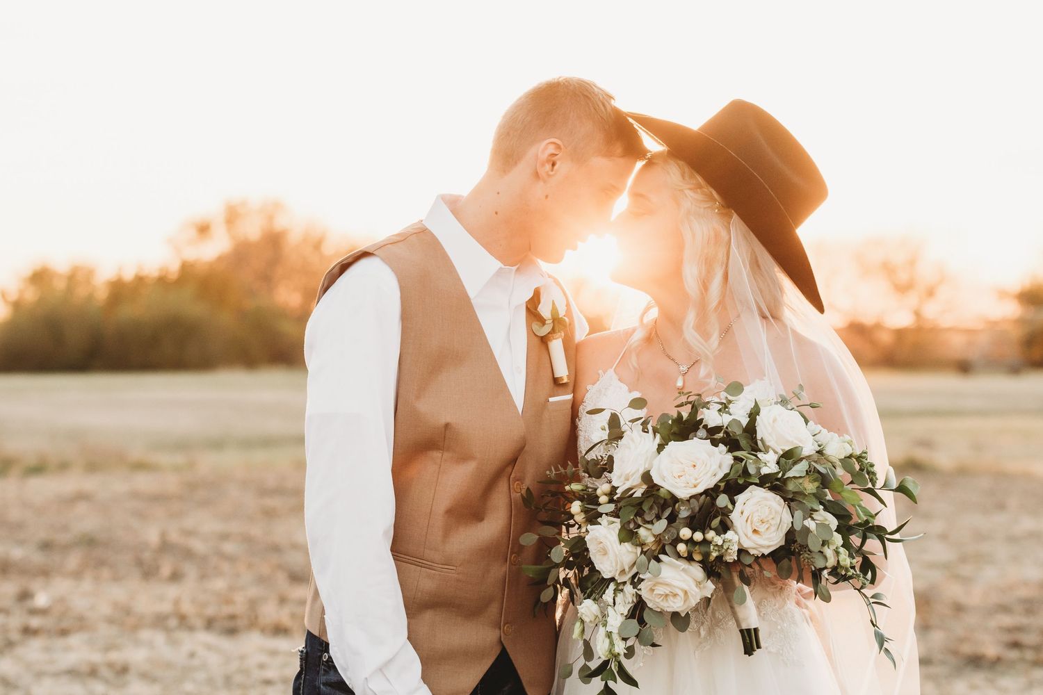 Bride holding white floral bouquet during sunset wedding photoshoot.