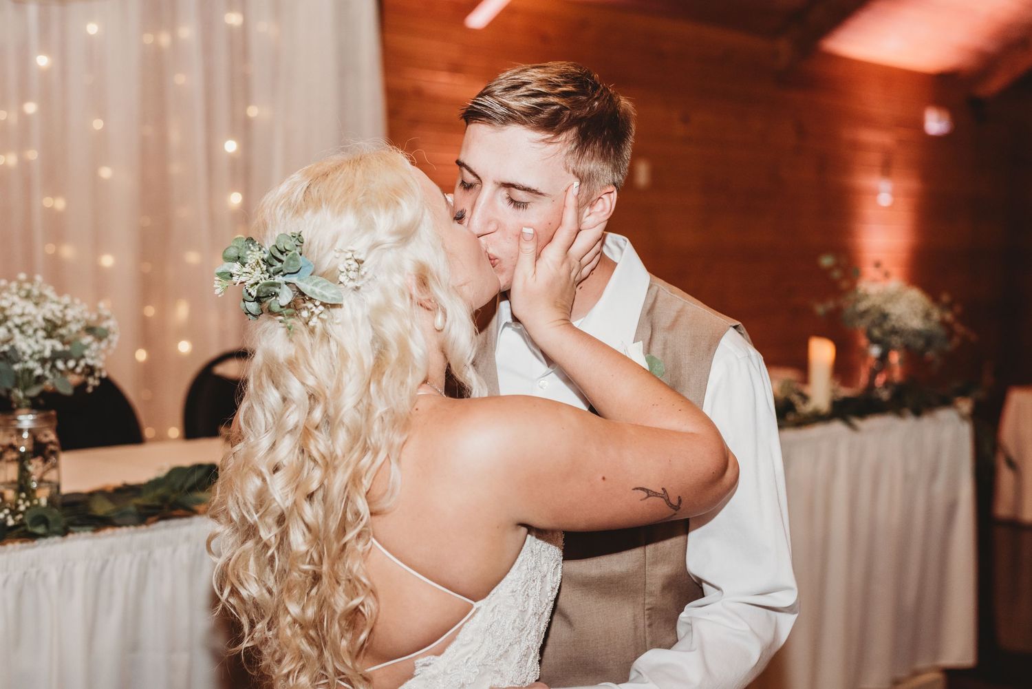 Intimate dance moment captured at wedding reception with warm lighting and draped backdrop.