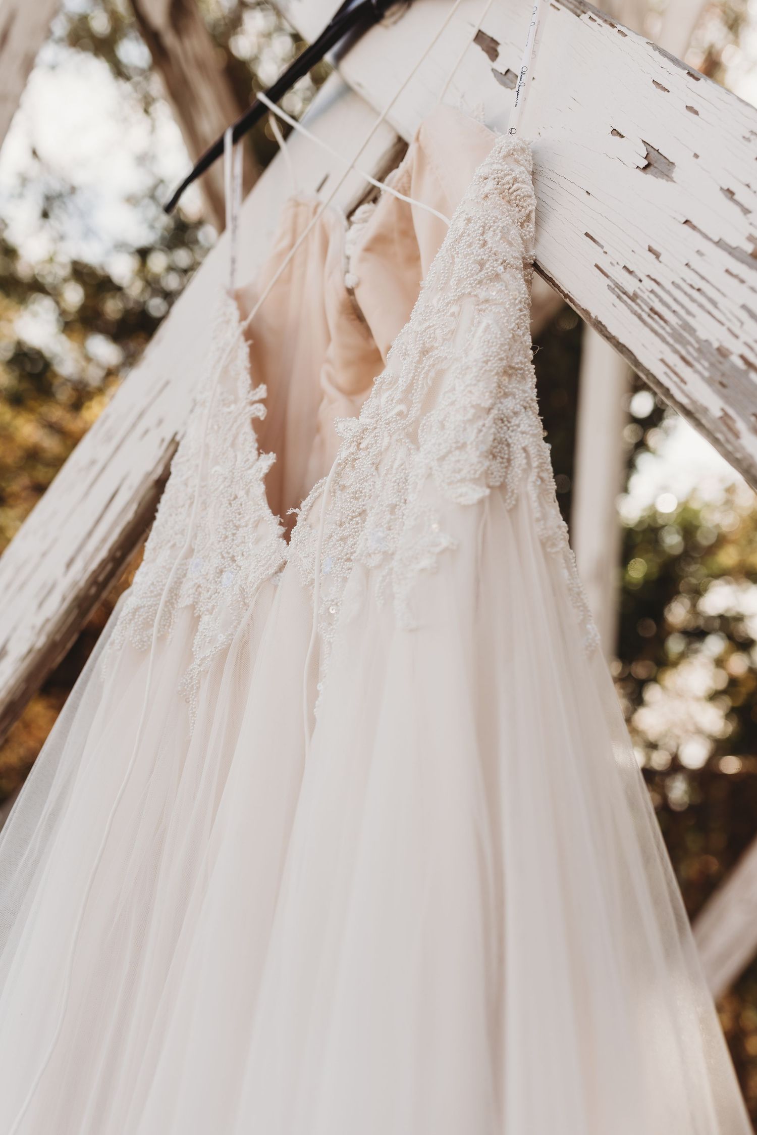 Collection of white wedding dresses hanging on display showing lace and tulle details.