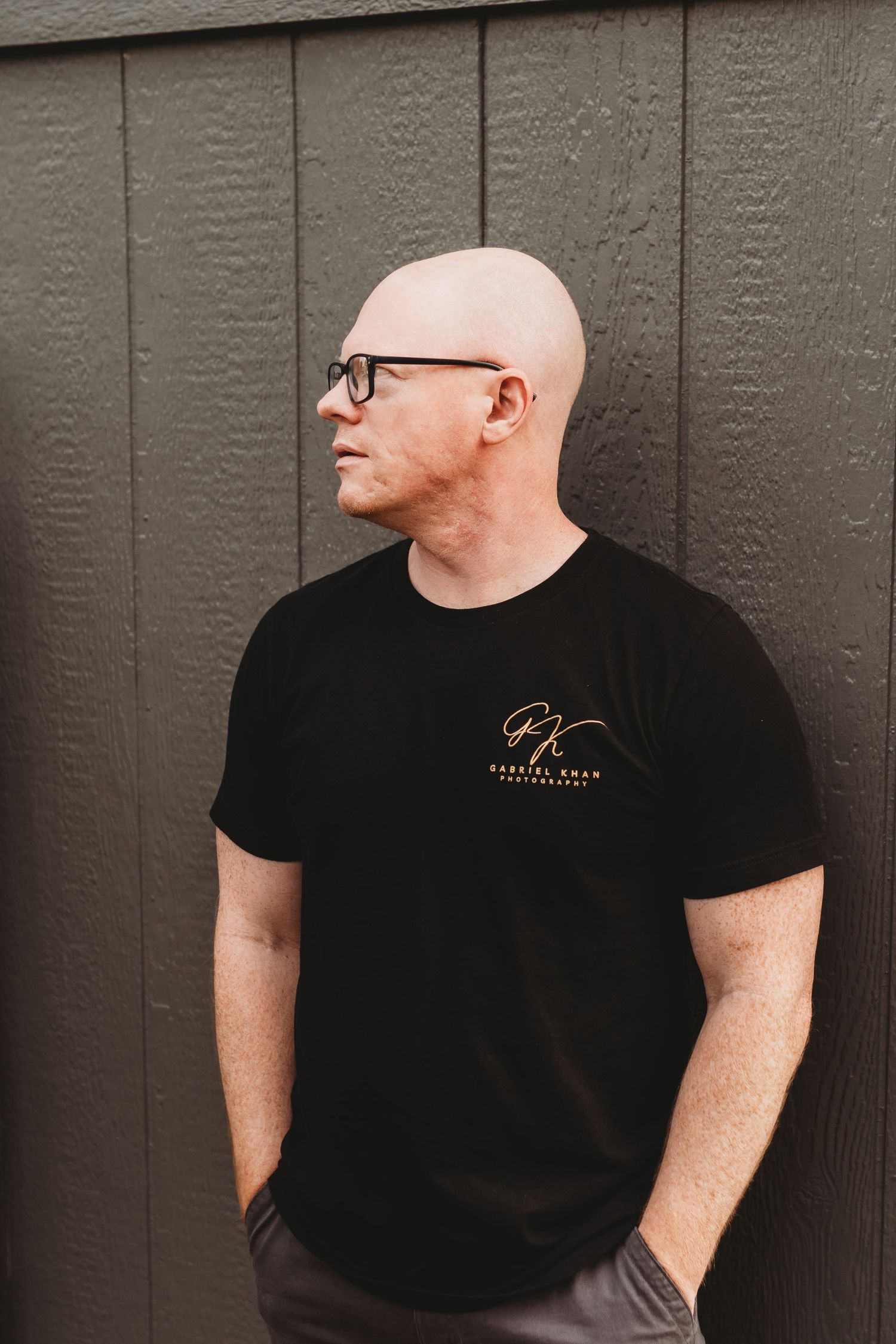 Side profile view of person in black t-shirt against grey wall.