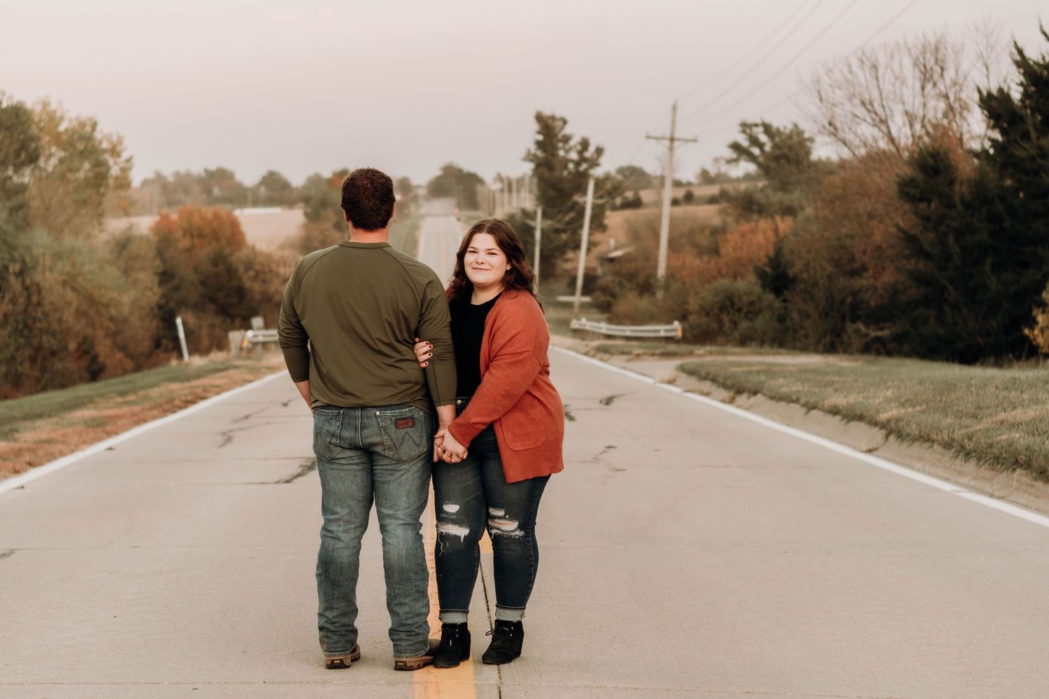 Couple walking together on empty rural road during sunset.