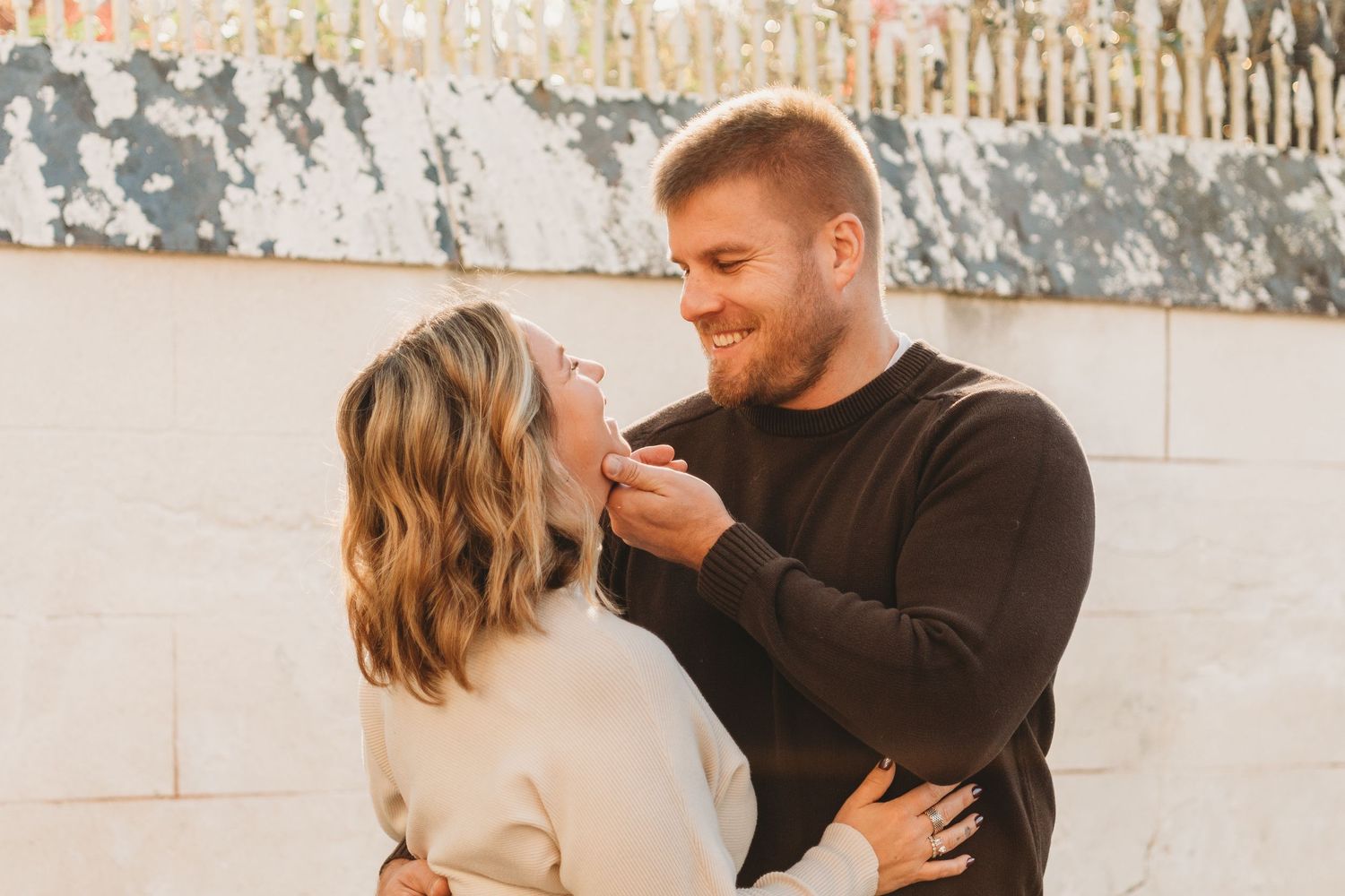 Couple sharing intimate moments in casual attire against neutral background.