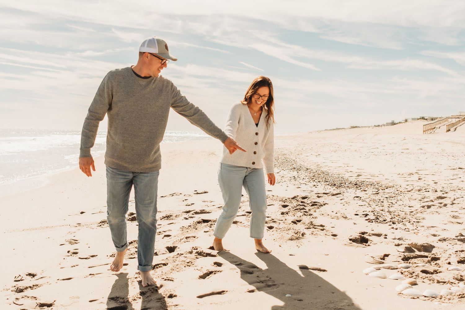 Couple walking along a sandy beach during golden hour.