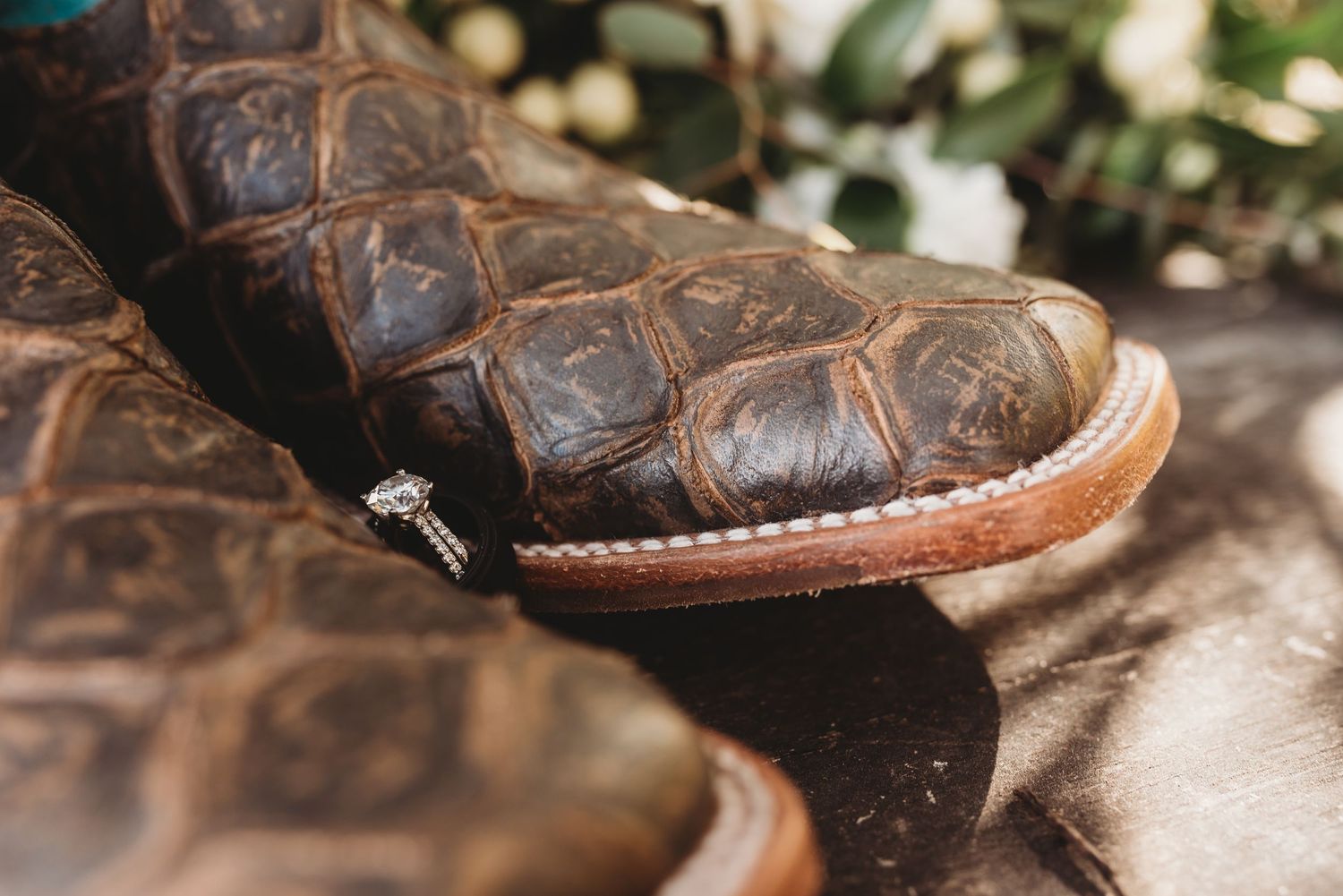 Vintage brown leather boots displayed among wedding decorations and greenery.