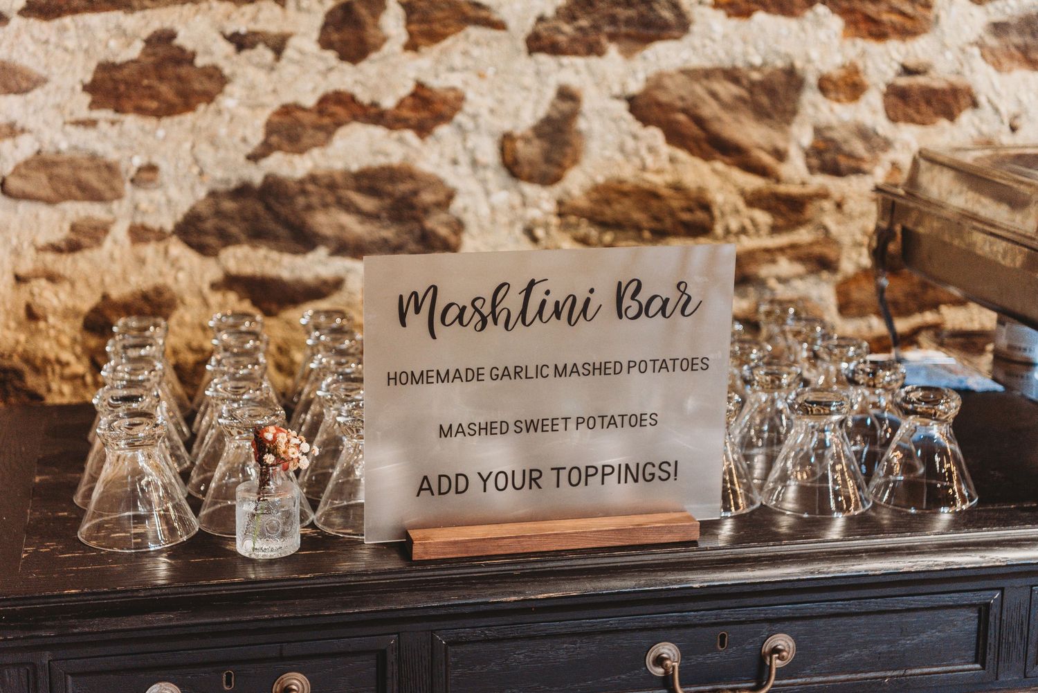Elegant drink station setup with custom signage and glassware at wedding reception.