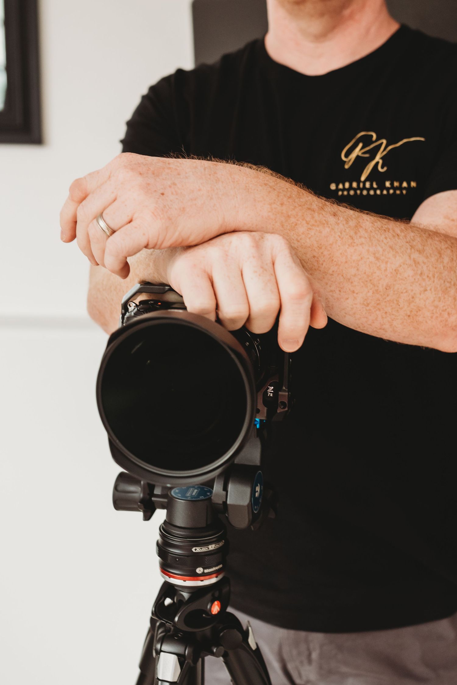 Close-up of hands adjusting professional camera equipment on a tripod.