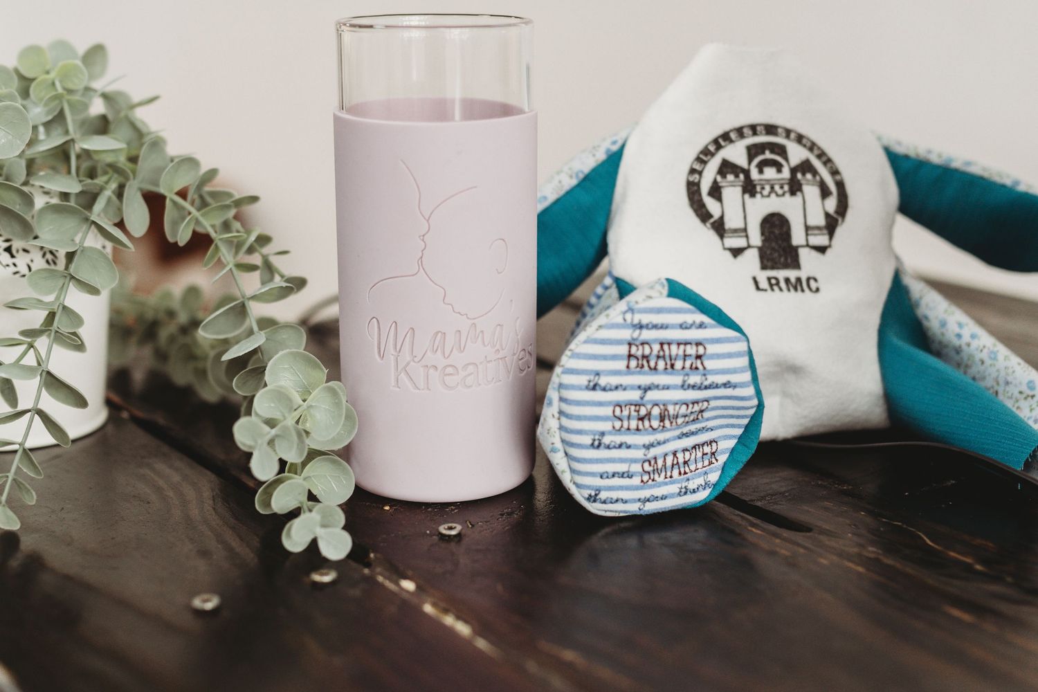Craft supplies and decorative items arranged on a white surface with greenery.