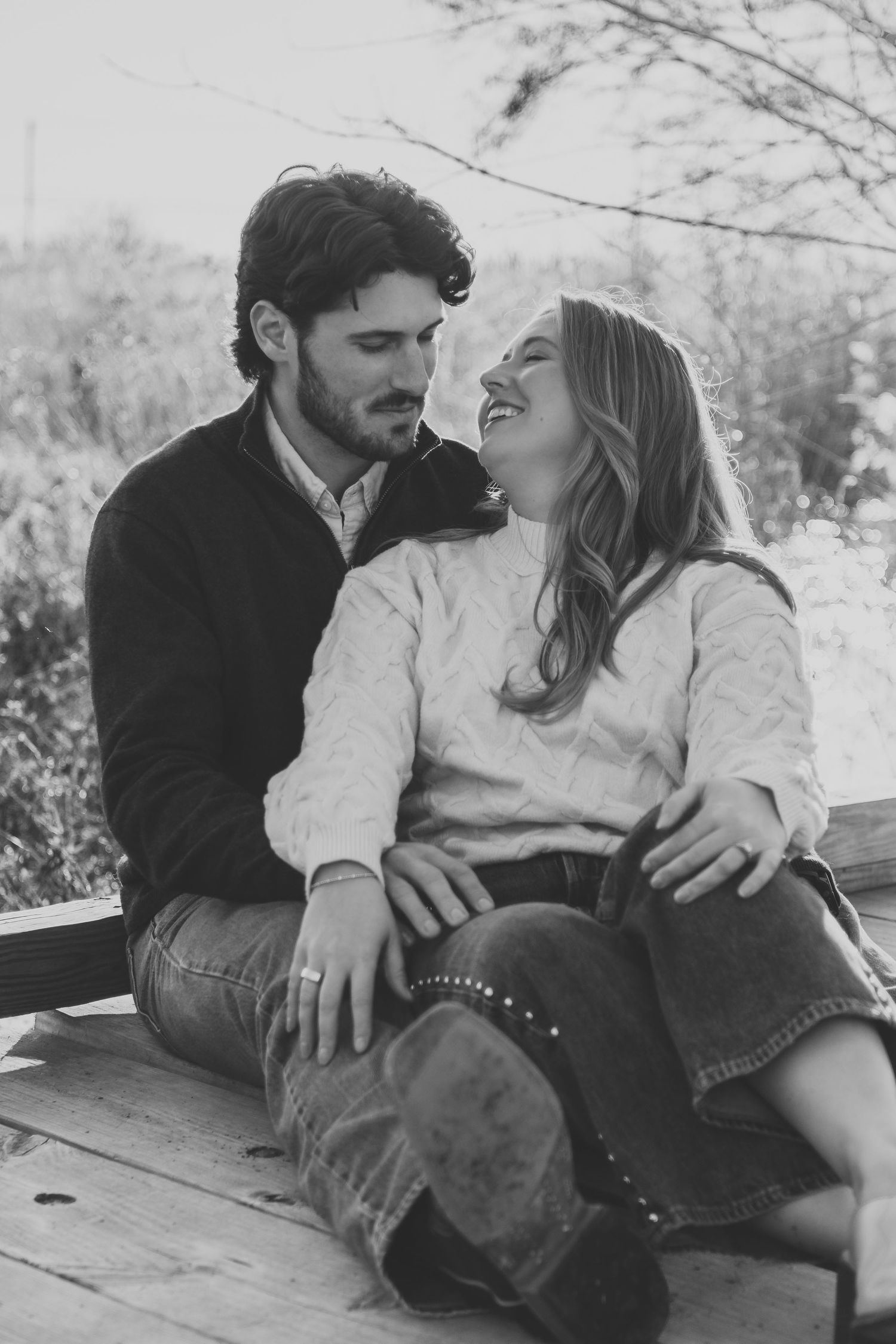 Black and white portrait of couple sharing intimate moments on wooden surface.
