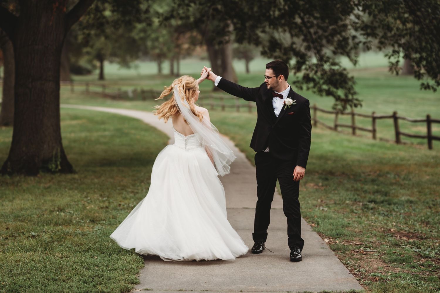 Wedding party walking together on a tree-lined path in formal attire.