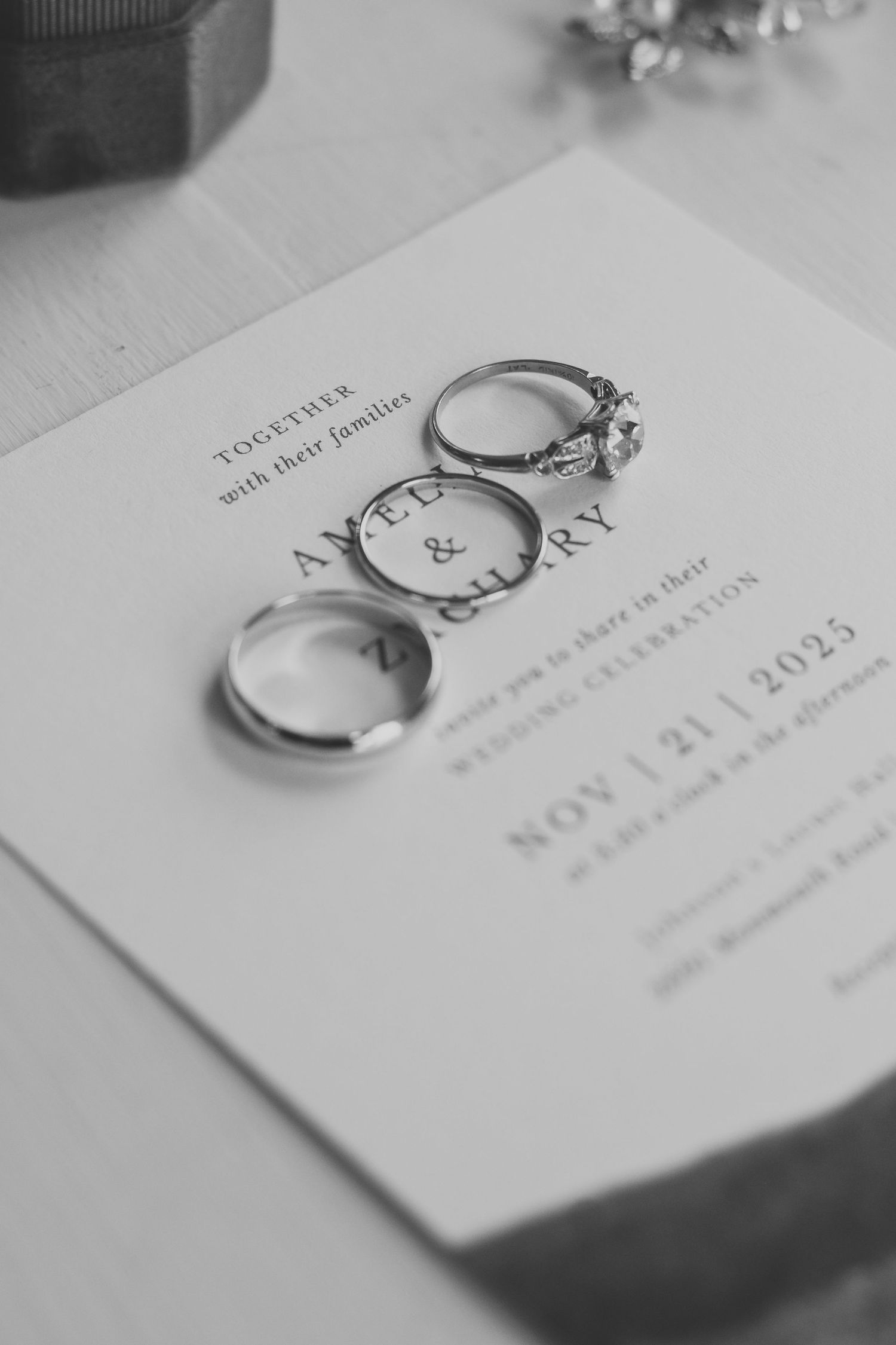 Wedding invitation with elegant rings placed on top in black and white.