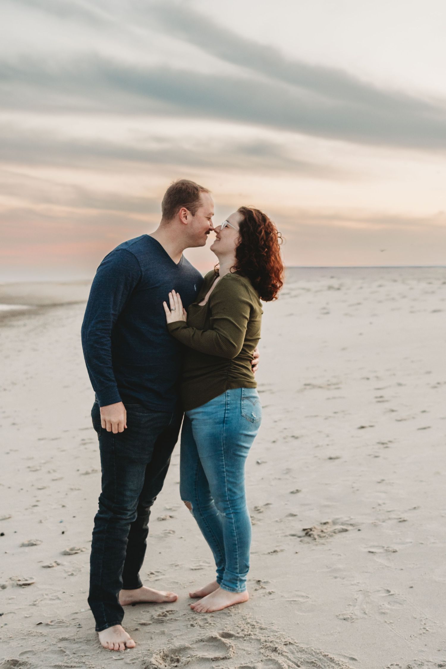 Couple sharing tender moment on empty beach at dusk.