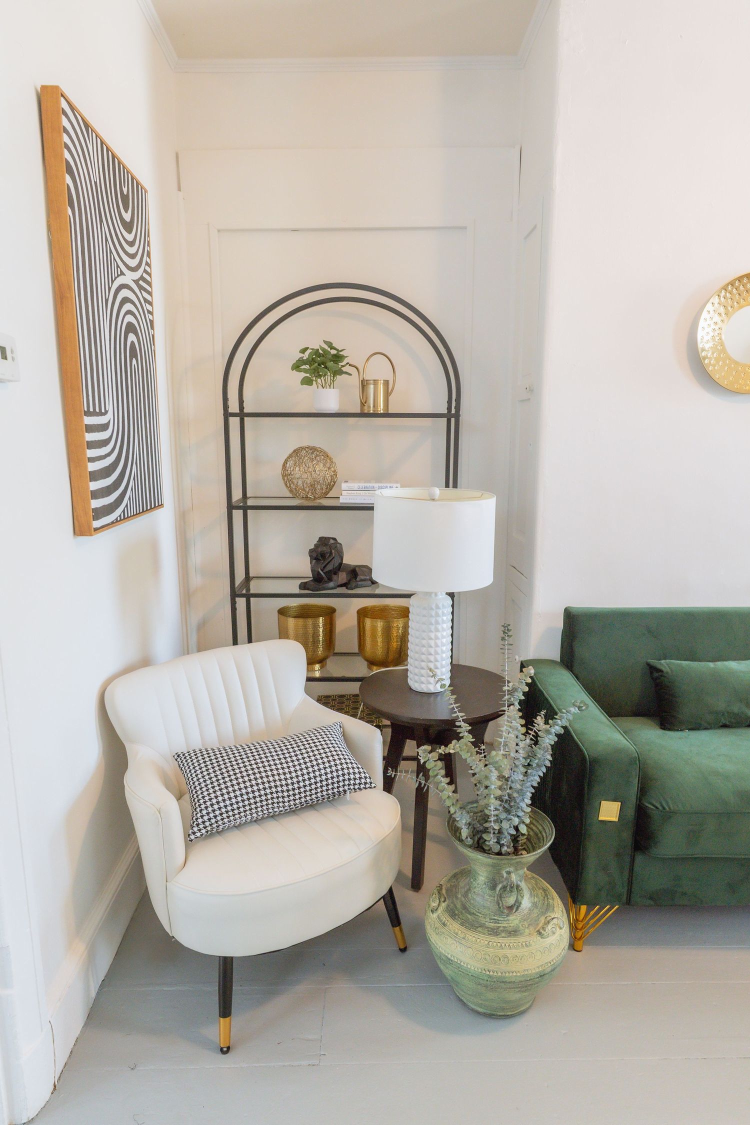 Contemporary studio interior with green sofa, white chair, and modern geometric wall art.