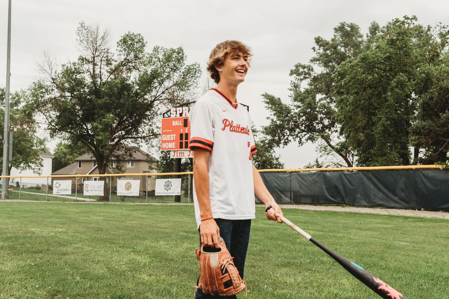 Baseball player practicing batting stance on green sports field.
