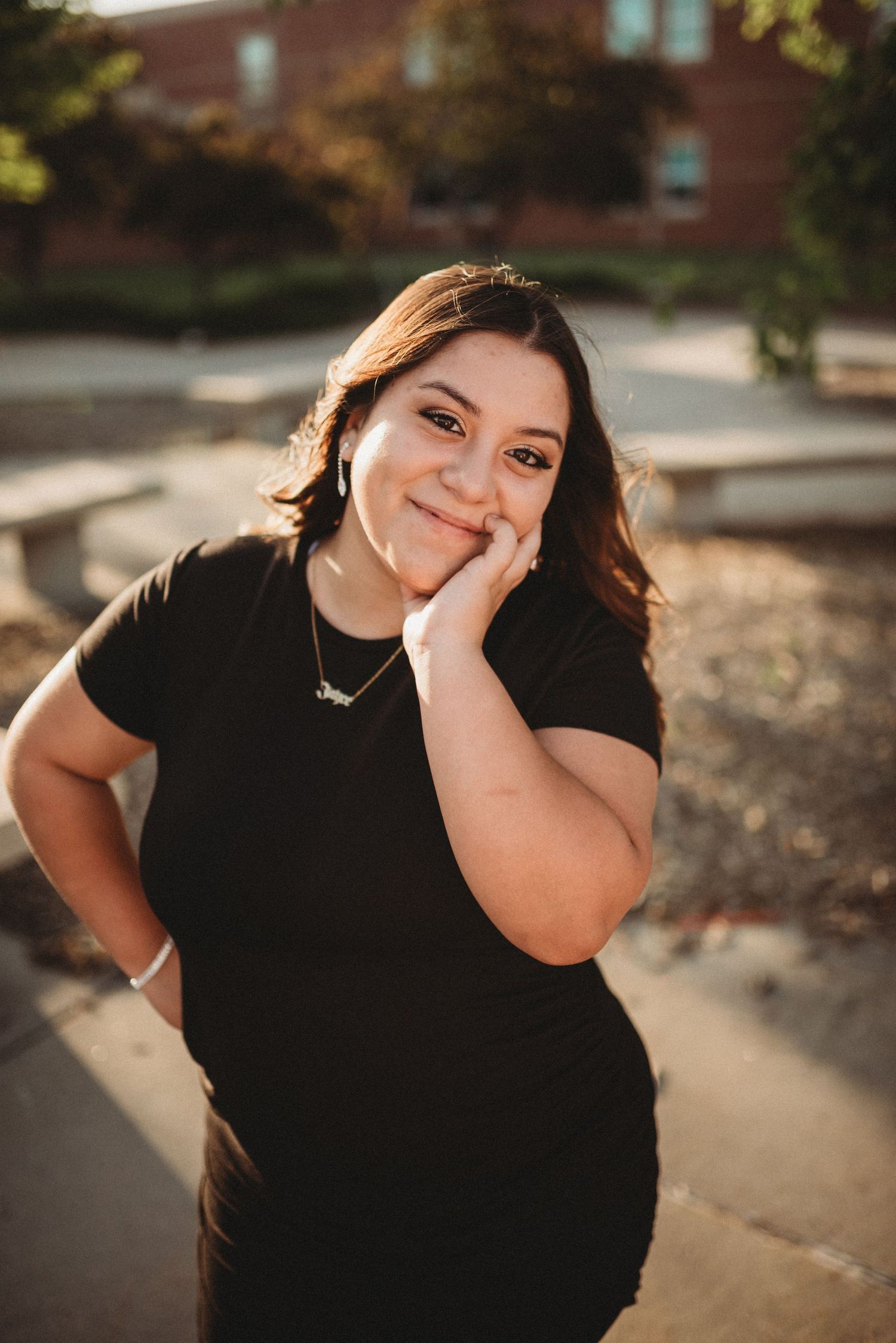 Woman in black shirt smiles and poses candidly during golden hour photoshoot.