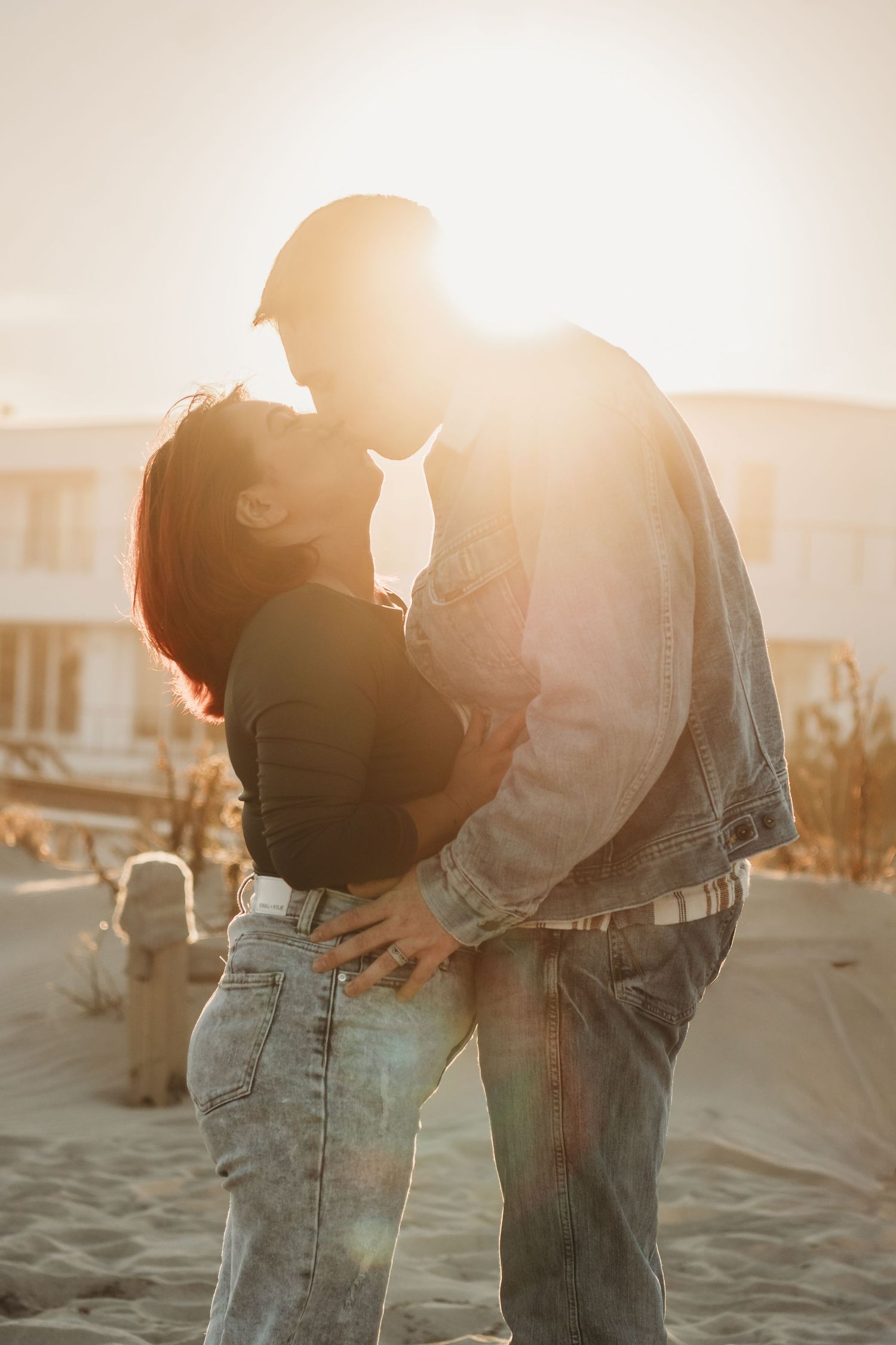 Silhouetted couple sharing an intimate moment on the beach at sunset.