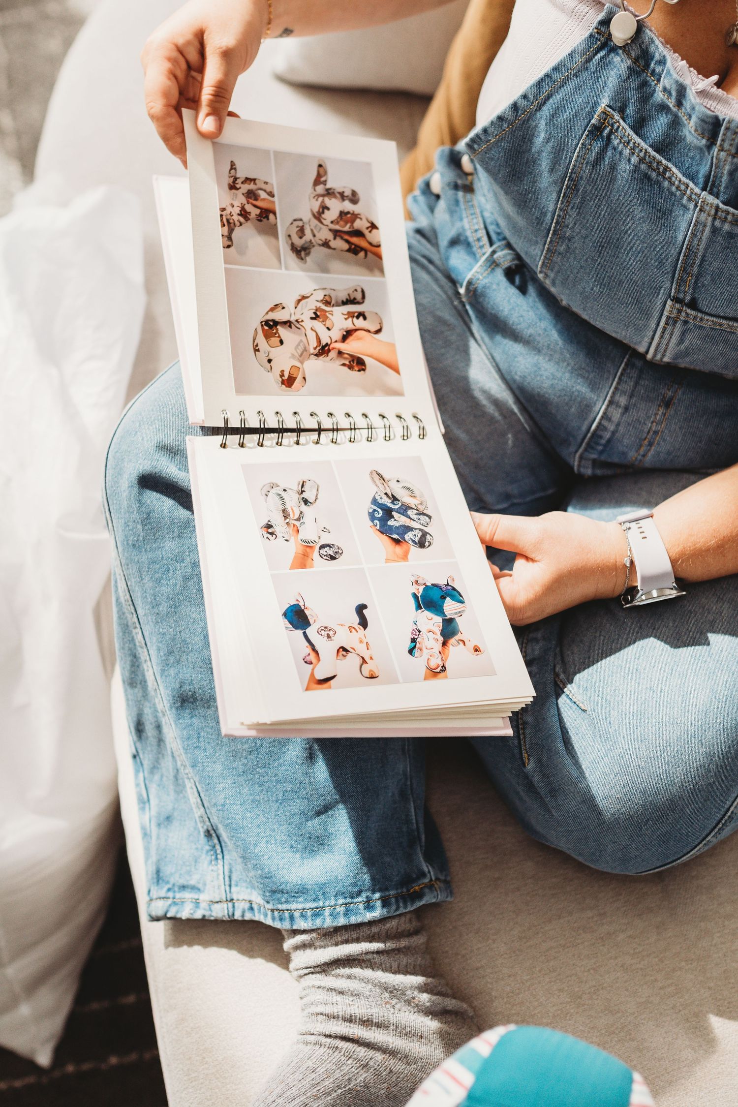 Person looking through craft project notebook while sitting on couch.