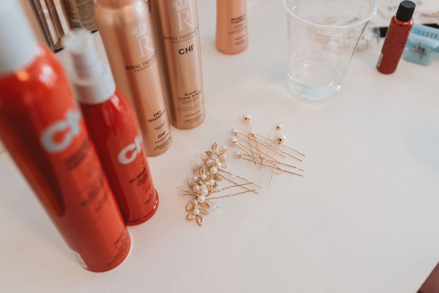 Makeup products and beauty items arranged on white surface for wedding preparation.