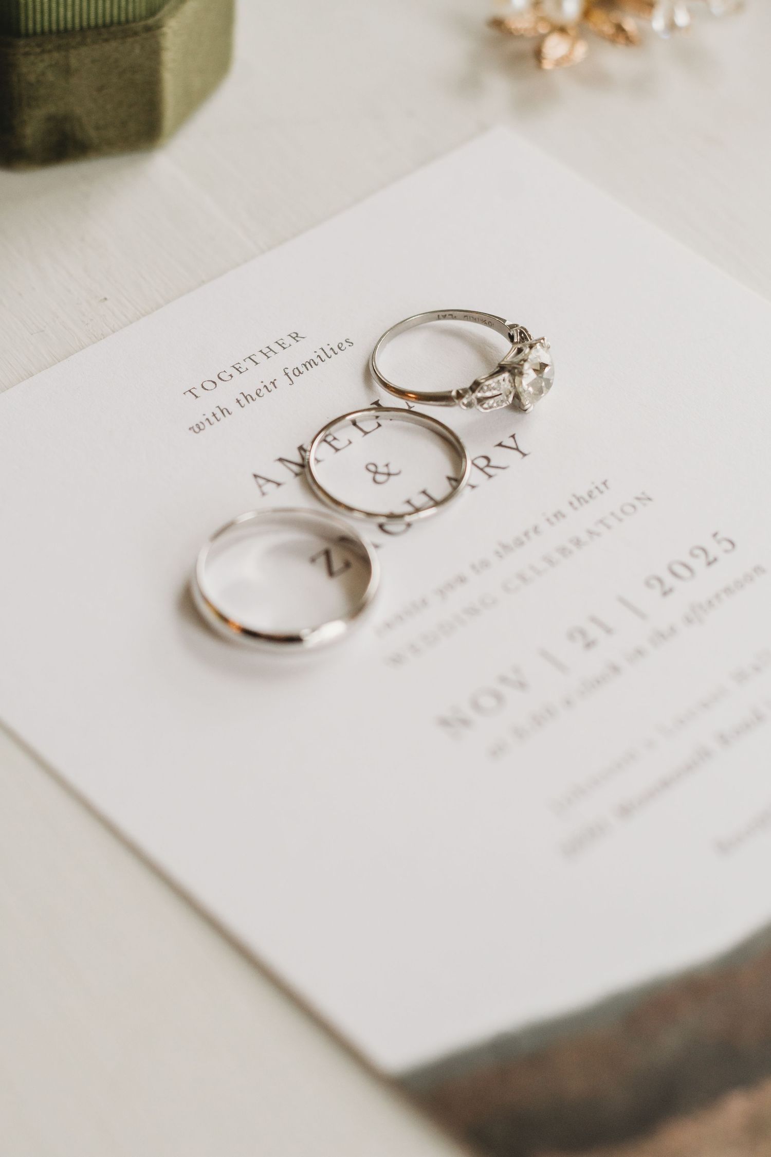 Wedding rings photographed on white invitation card with elegant typography.