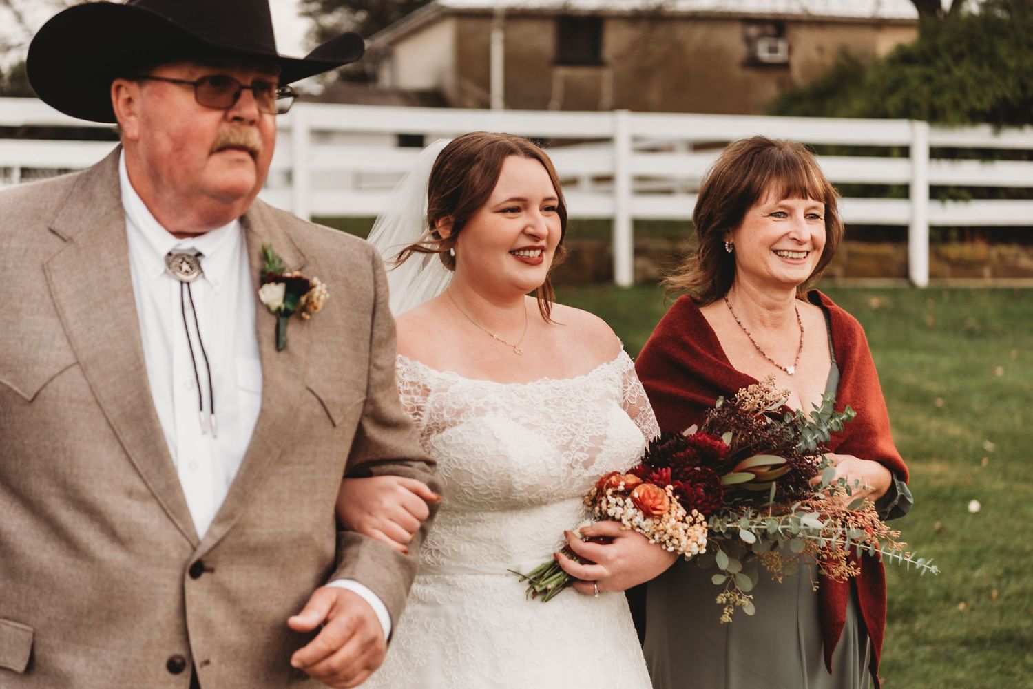Wedding party posing outdoors with rustic farm fencing in the background.