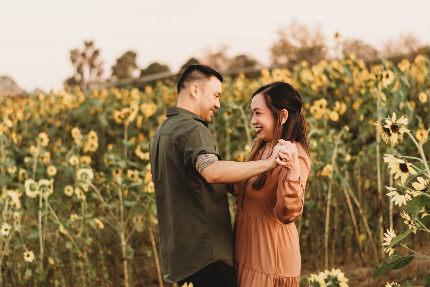 Couple sharing intimate moment in sunflower field during golden hour.
